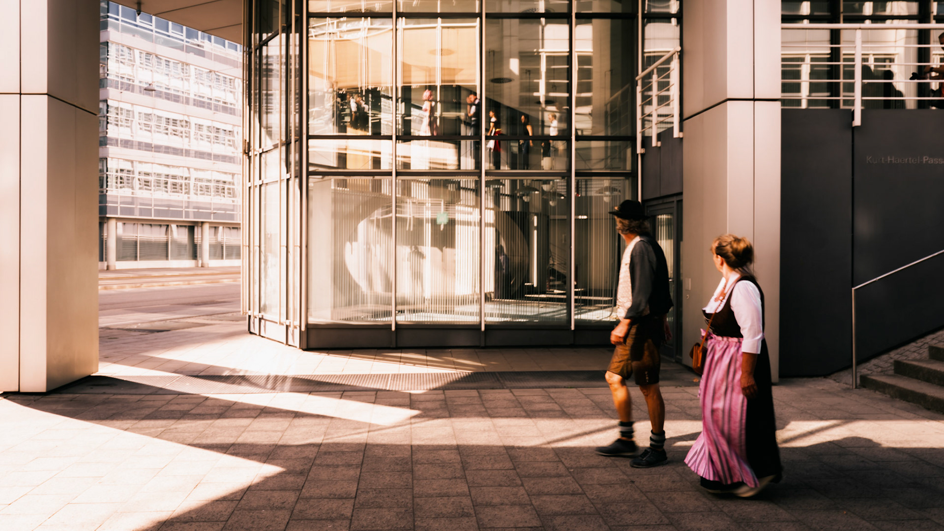 in the heart of munich, people clad in traditional bavarian tracht stride towards the oktoberfest festivities. the contrast of old-world attire against the modern architecture highlights the blend of tradition and progress. the atmosphere is charged with anticipation, as the city embraces its heritage during the world-famous celebration.