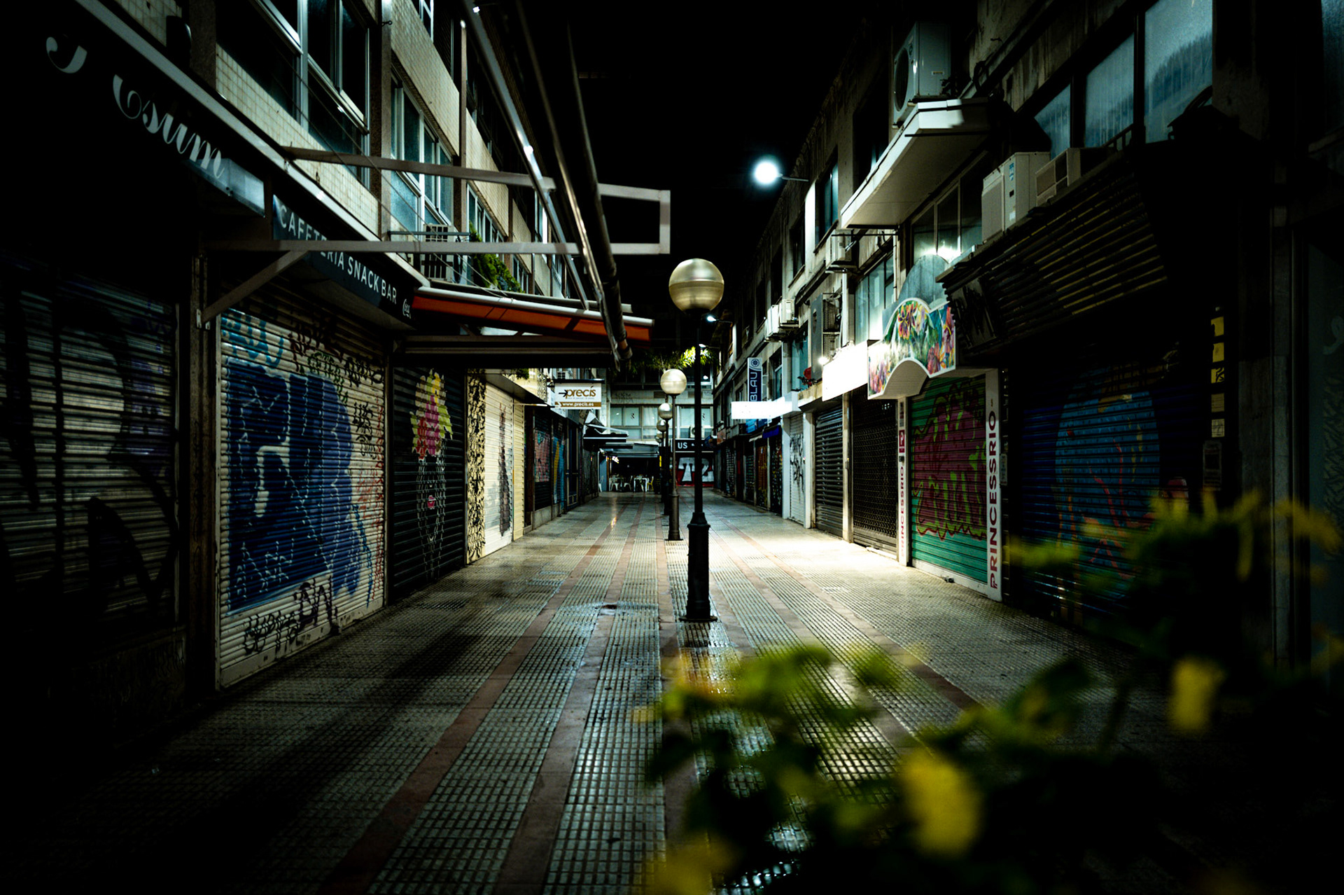 In the hushed heart of palma lies the galerias velazquez, an old commercial hub now cloaked in the night's embrace. Shadows stretch across the empty walkways, where the buzz of day is replaced by stillness. The closed facades, once bustling with life, stand silent under the streetlights' glow, whispering tales of days gone by. Here, the city's pulse slows, and the night watches, a guardian of the quiet urban landscape.