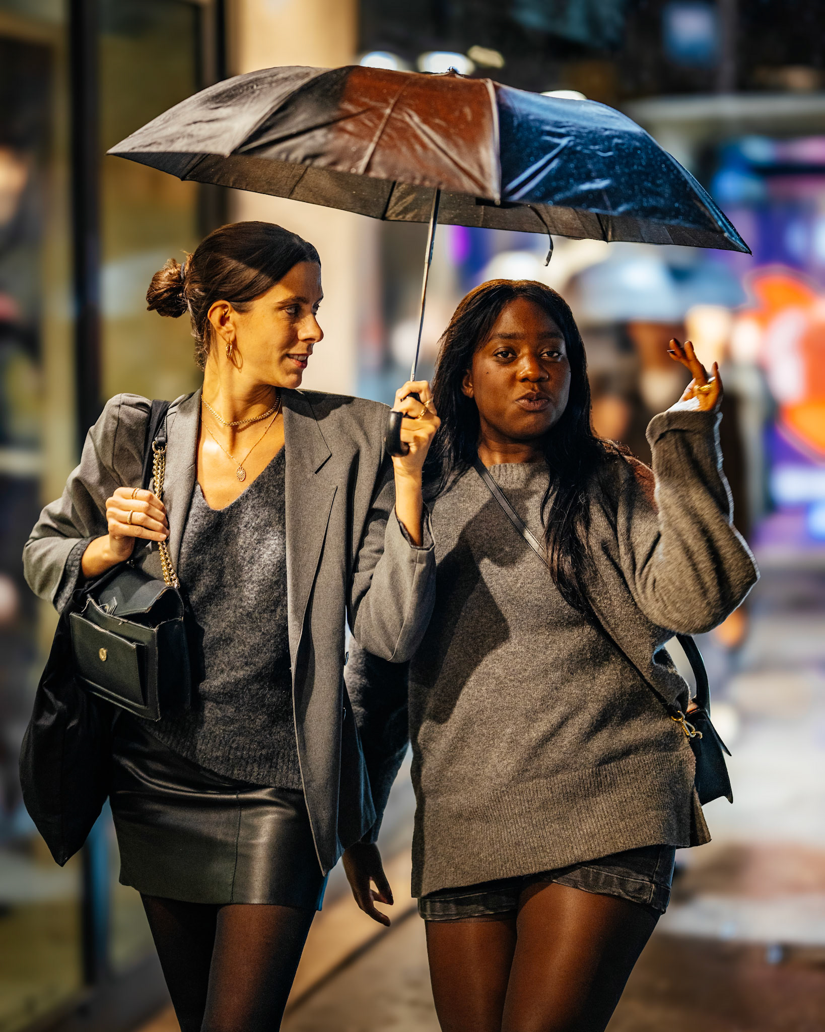 late night rain, warm city lights, and two friends strolling through it all. the umbrella shelters them from the weather, but their laughter and closeness light up the night even more. a candid moment that reminds us of the beauty in simple, shared walks.