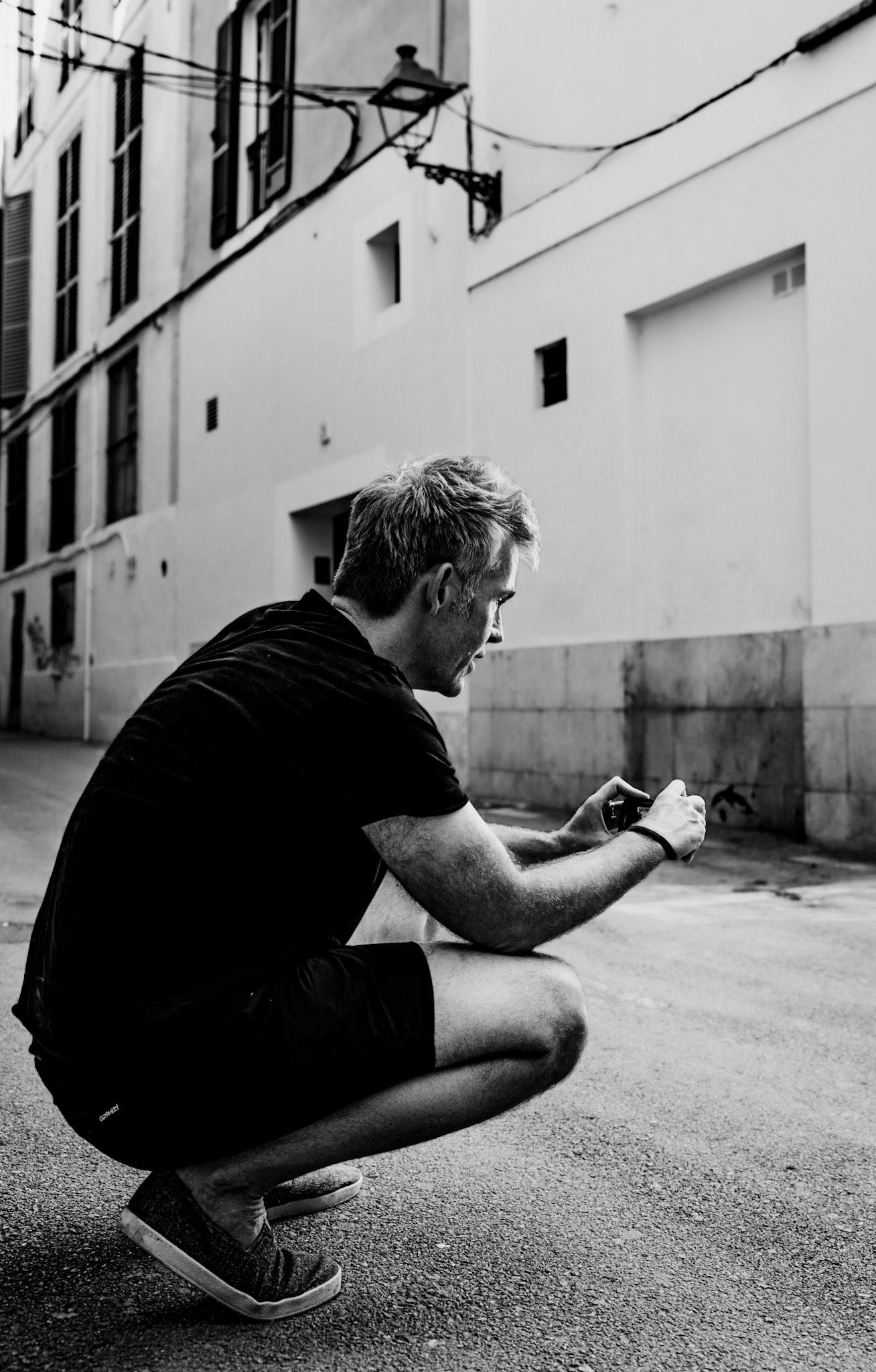 as thomas, a fellow street photographer, crouches in a quiet corner of palma, his focus sharpens, the streets and shadows converge in his mind to create the perfect composition. this moment captures not just his creative process, but the dedication and thought behind each shot—a silent dialogue between the artist and his urban canvas. together, we explore the city's angles and stories, each frame a reflection of our shared passion for photography.