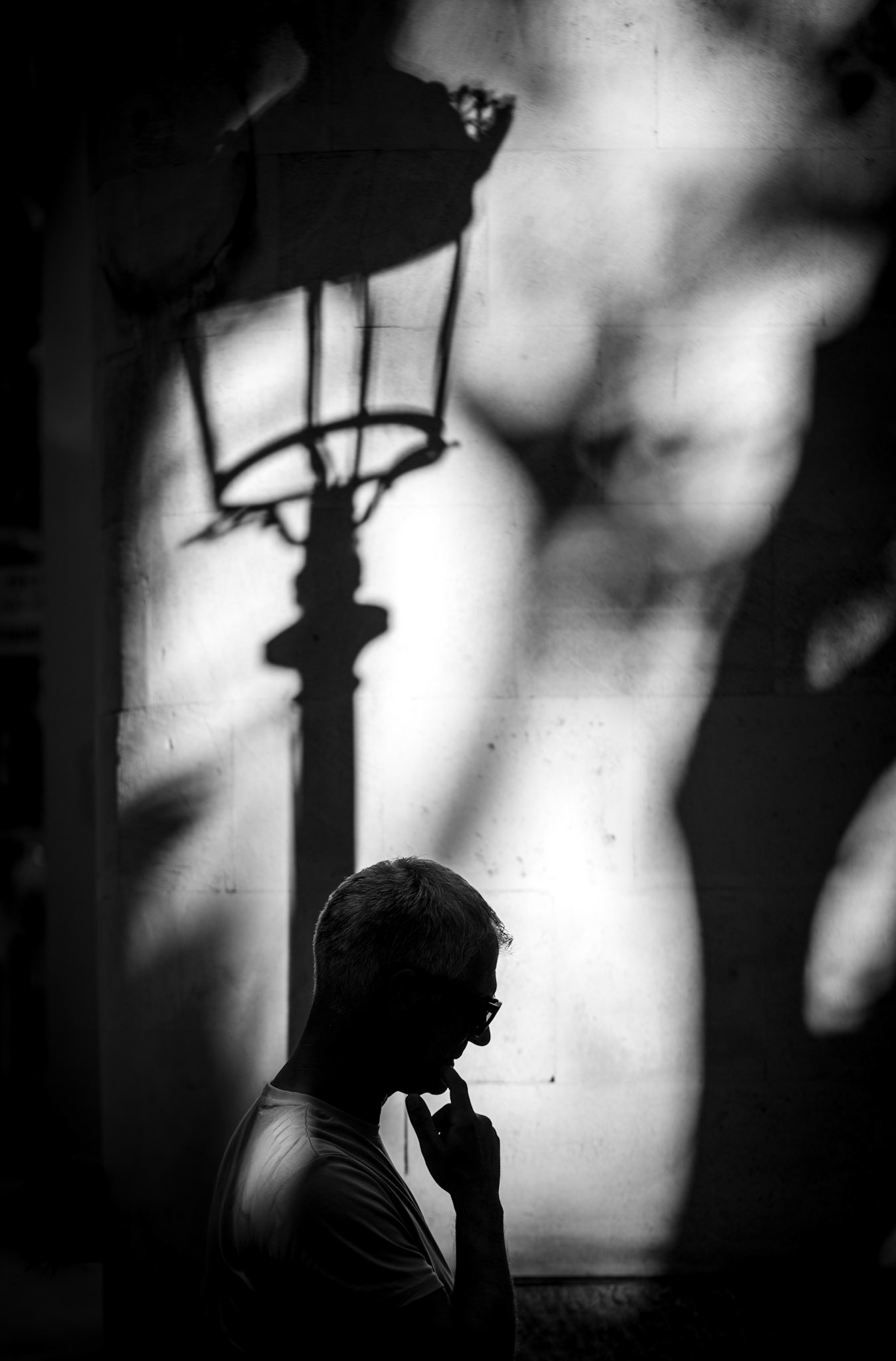captured in palma de mallorca, this photo depicts the silhouette of a man deep in thought, with the shadow of a street lamp cast above him. in german, there is a saying "ein licht geht auf," which means "a light goes on" when someone finds a solution or understands something. the interplay of light and shadow in this image beautifully symbolizes the moment of realization and clarity.