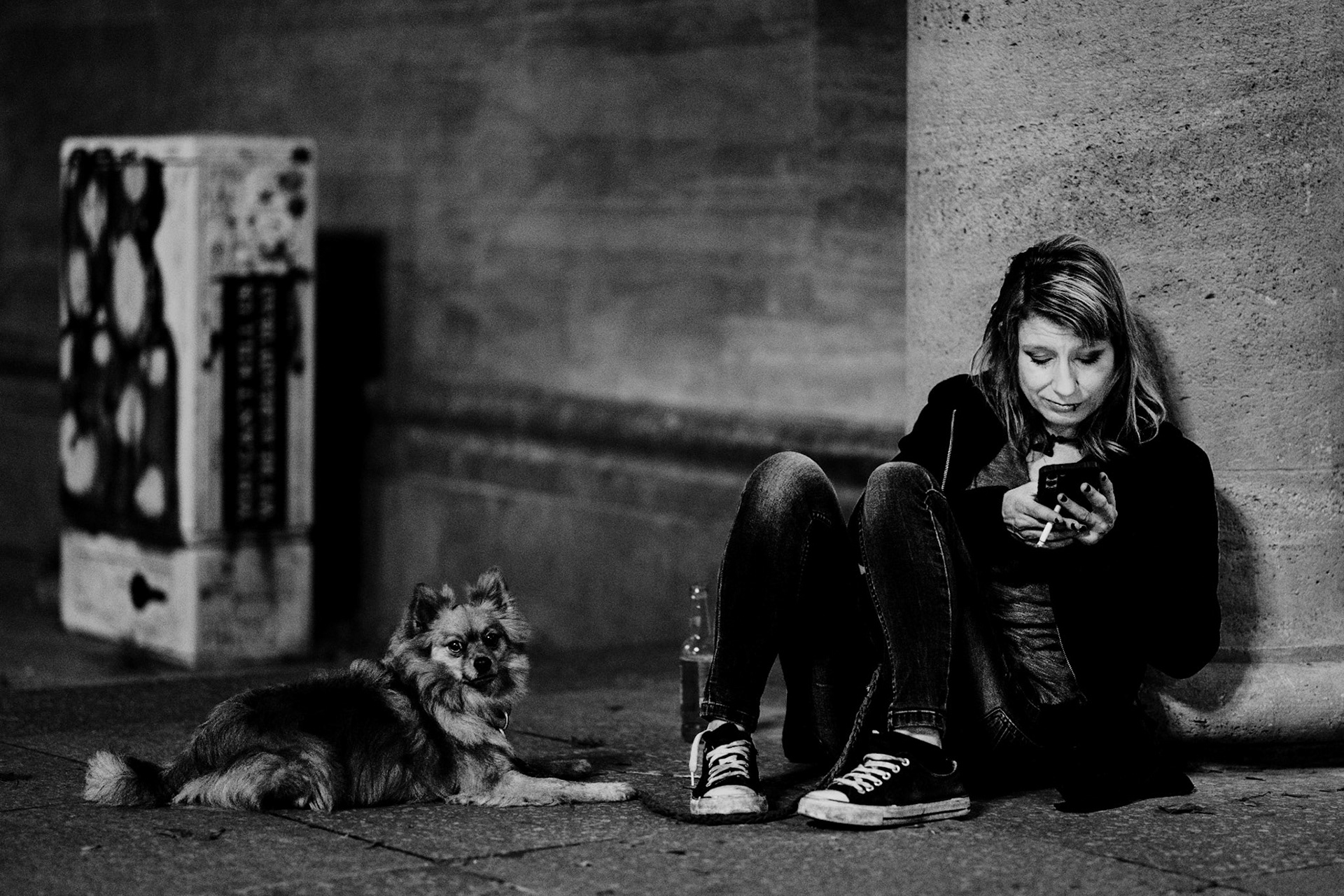 beneath the pillars of a quiet night, she sits with her loyal companion. the city moves, but here, time stands still. a cigarette burns slowly, a phone glows faintly, and the dog rests in quiet contentment. two souls sharing a stillness, each immersed in their own world yet undeniably connected.