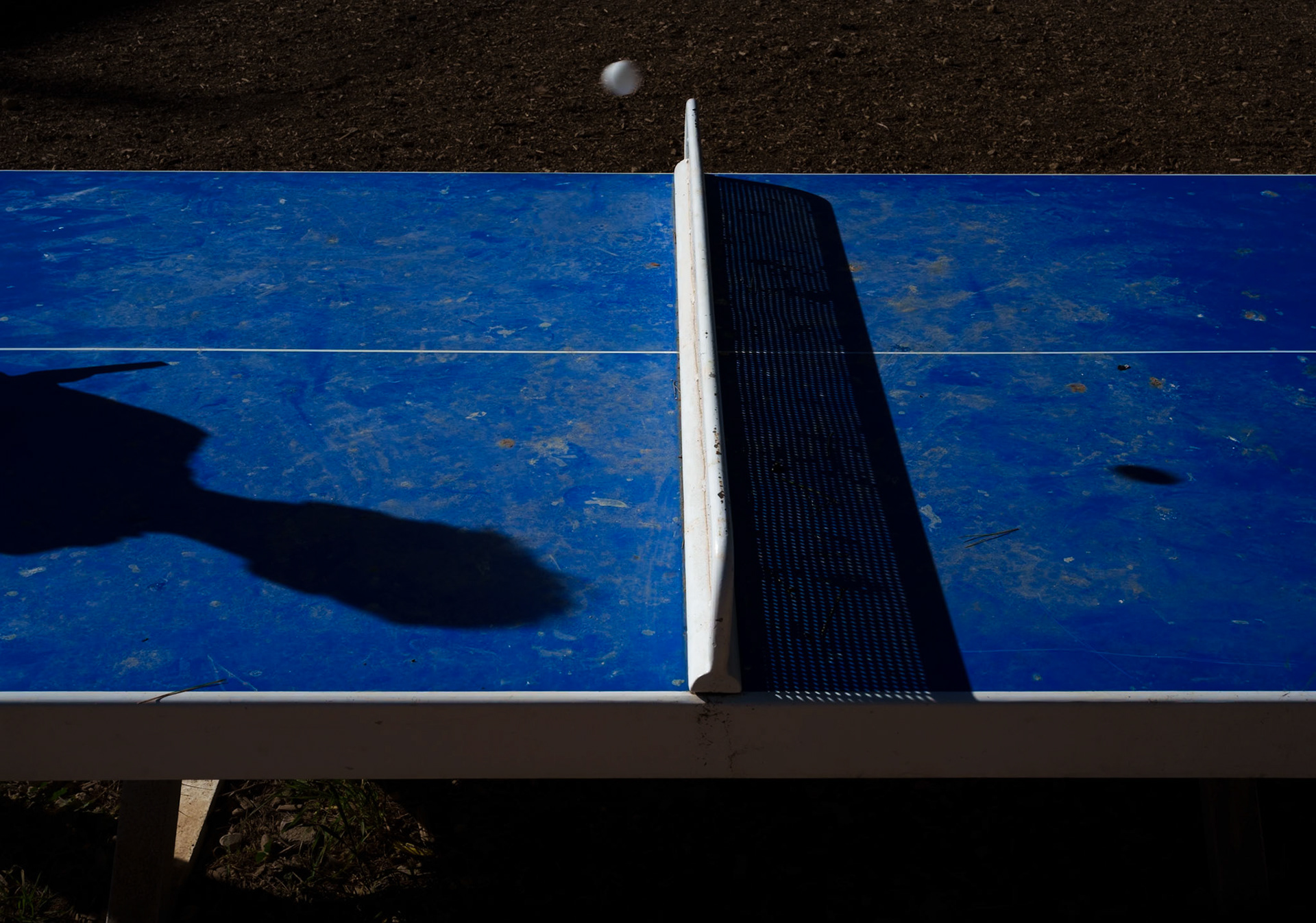 captured at the playground in the bellver parc, this photo is part of "a morning at the playground" series. the winter sun casts long shadows, creating a stark contrast against the vibrant red safety surface. the playground stands quiet, its colorful spring rider poised in stillness, waiting for the laughter and chaos of play that comes with the warmer days.