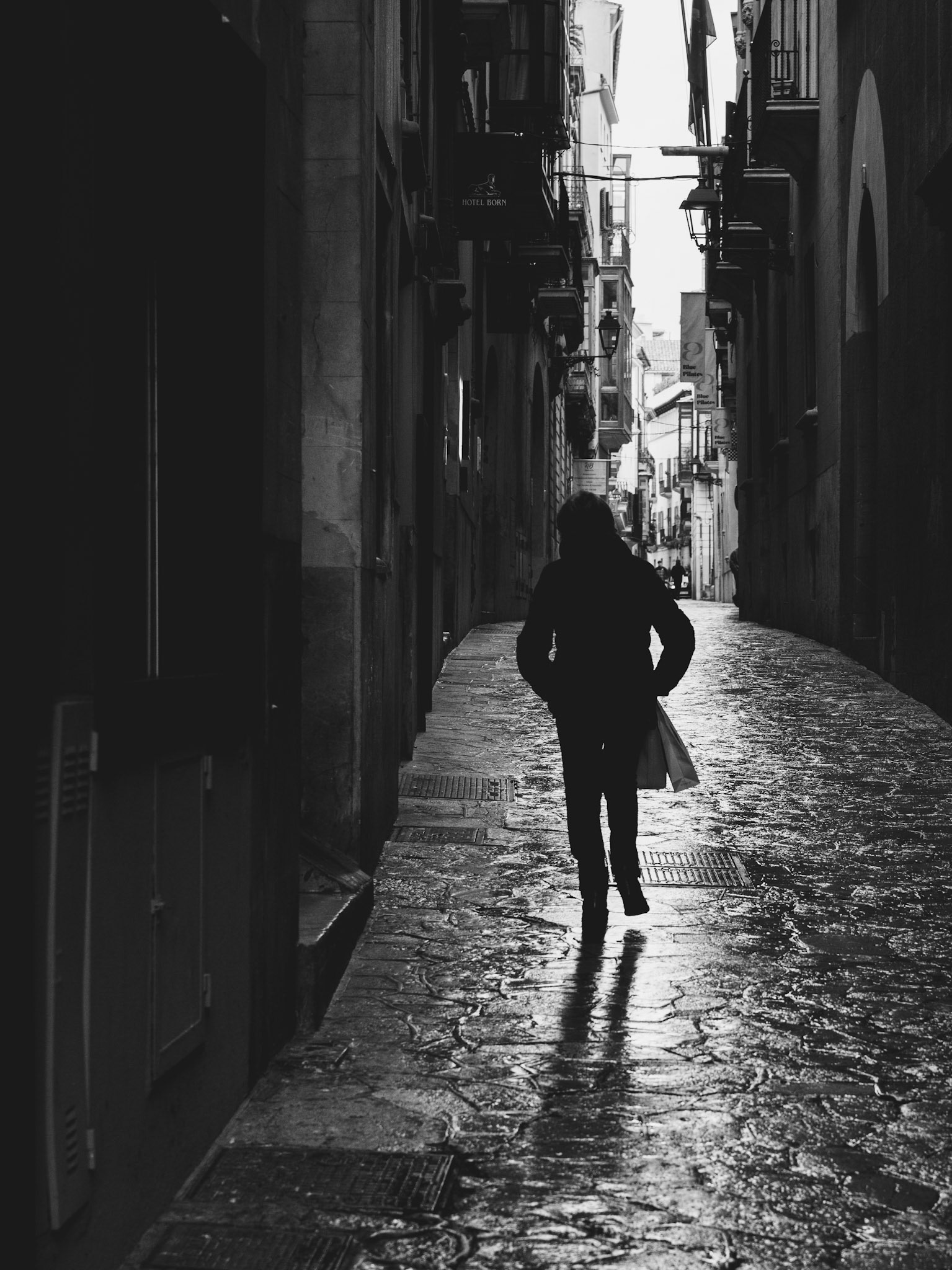 after the rains have swept through the heart of palma de mallorca, the cobbled streets glisten with the stories of the city. a solitary figure walks away, their back to us, as if carrying the weight of the wet, reflective path under their feet. the old buildings lining the narrow alley whisper tales of times past, their windows dark and watching. the rain has quieted the usual bustle, leaving behind a scene of contemplative solitude, where every step echoes against the stones and the history of this island capital.