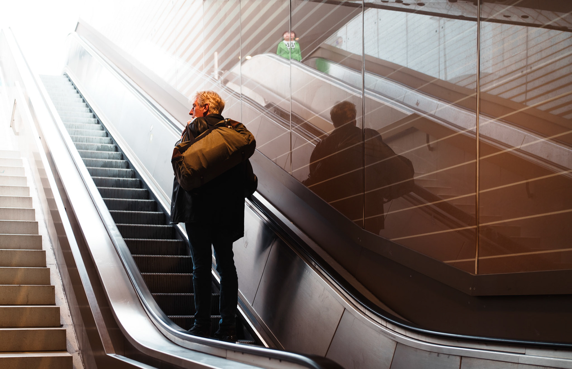 taken by my eight-year-old son in a munich subway station with the sony a7cr i loaned him, this photo captures a moment of transition and reflection. a man, carrying a large bag over his shoulder, ascends the escalator. the glass wall beside him mirrors his figure, enhancing the sense of movement and travel. light gently filters from above, illuminating the scene, while the parallel lines of the stairs and escalator create intriguing geometry. the use of automatic settings and lightroom post-processing helped highlight the colors and contrasts, making the image crisp and vibrant. this photo illustrates how even a simple moment in a subway station can tell a story, especially when seen through the lens of a child.