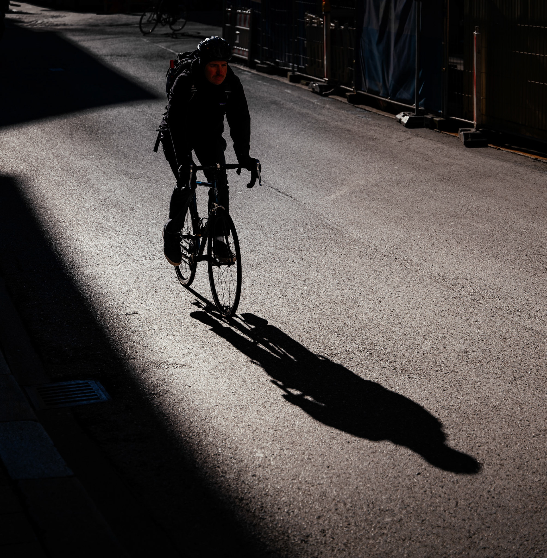 morning light spills onto munich's center, painting paths with a golden brush. amidst this interplay of light and shadow, a cyclist becomes the artist, his two-wheeled steed casting a long, dark echo on the concrete canvas. pedaling through the cool air, his form is hunched in concentration, a solitary figure on the urban stage where the sun directs a daily performance. every turn of the wheel is a silent note in the city's waking symphony, a fleeting connection between the still-slumbering world and the break of day.