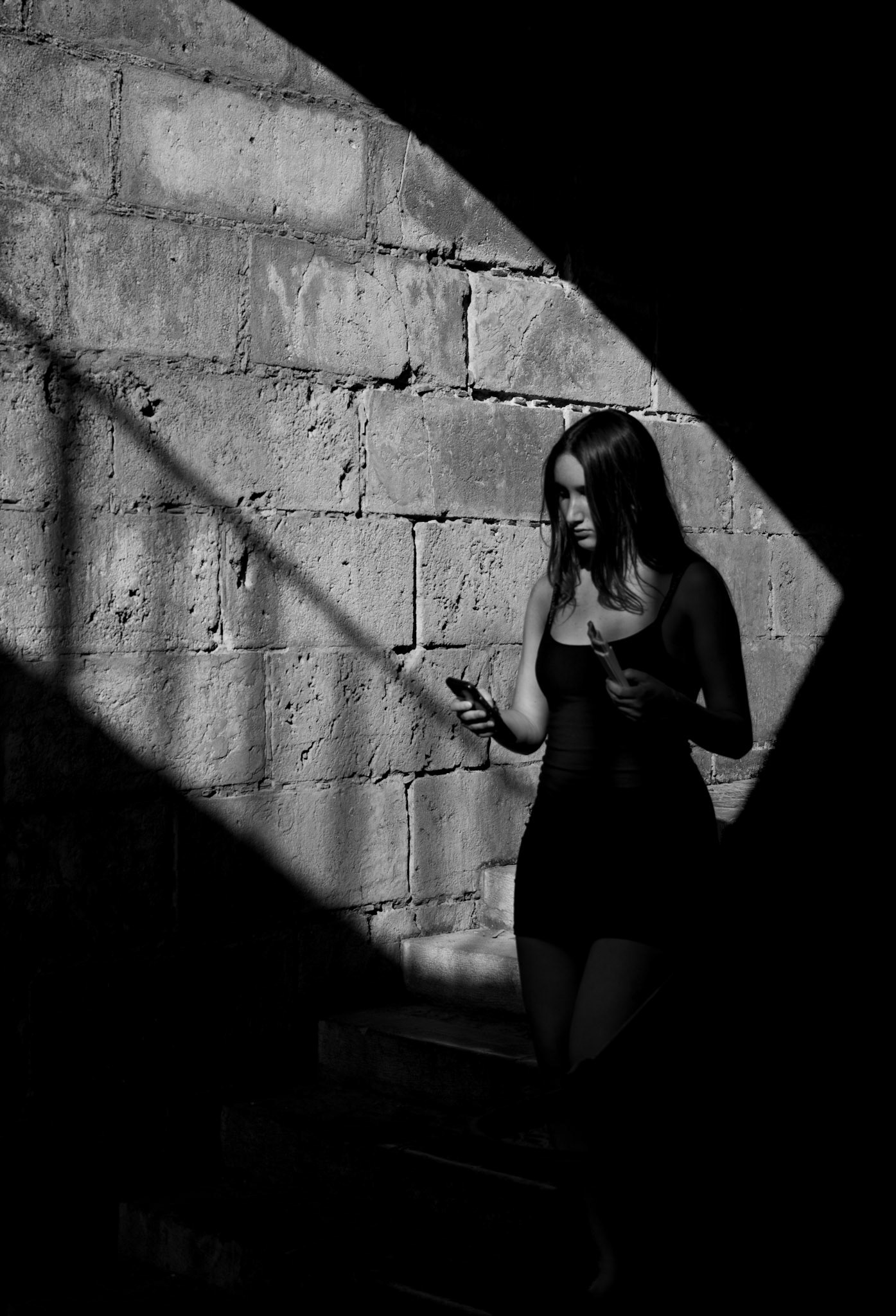 a quiet moment caught between the play of light and shadow, this scene captures a fleeting second of introspection. the rough stone wall and the diagonal beam of light create a stark contrast that highlights the figure without revealing too much. it's a visual whisper of solitude, movement, and the in-between spaces where we often find ourselves lost in thought. there’s a haunting beauty in how the light touches just enough, leaving the rest to imagination.