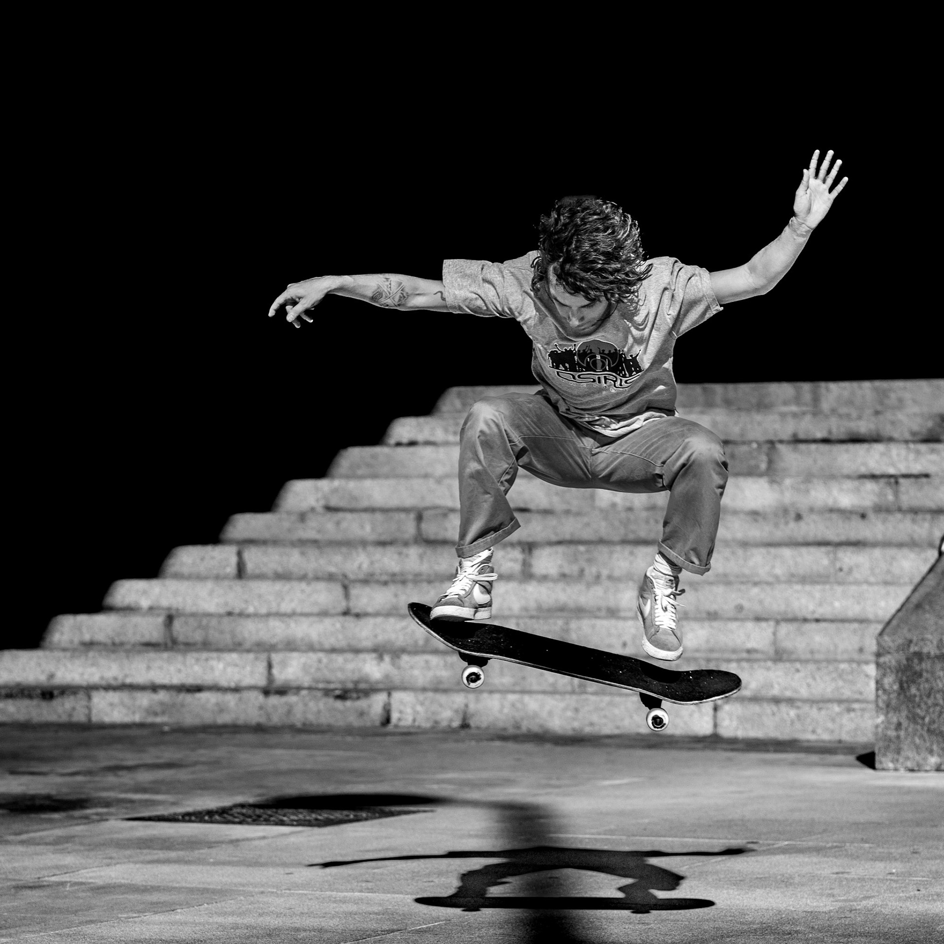 captured in madrid, at the steps of plaza de la puerta cerrada, this photograph freezes a fleeting moment where youth dances with gravity. the skateboarder, airborne and perfectly balanced, seems to defy the very force that pulls us down. the background, a silent witness in shadow, contrasts with the skater’s dynamic energy, almost as if the city holds its breath in anticipation. the tension in his outstretched arms and the arc of the board mirror each other, creating a visual rhythm that echoes the pulse of the streets. this is not just a trick—it's a statement, a challenge, a moment when time itself seems to pause.