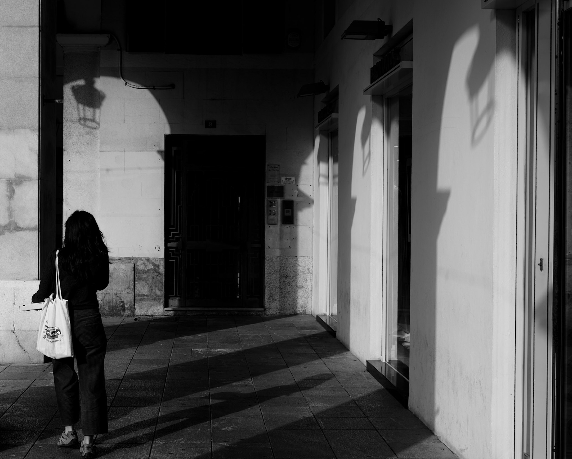 at placa mayor in palma, the morning light plays a silent concert of contrasts. a lone walker, her form just a whisper against the architecture, moves through the symphony of shadows and beams. the city breathes in monochrome, each corner a potential story, each window a silent witness to the steady rhythm of steps on stone. this is a moment where light, space, and solitude harmonize in the quiet theatre of the everyday.