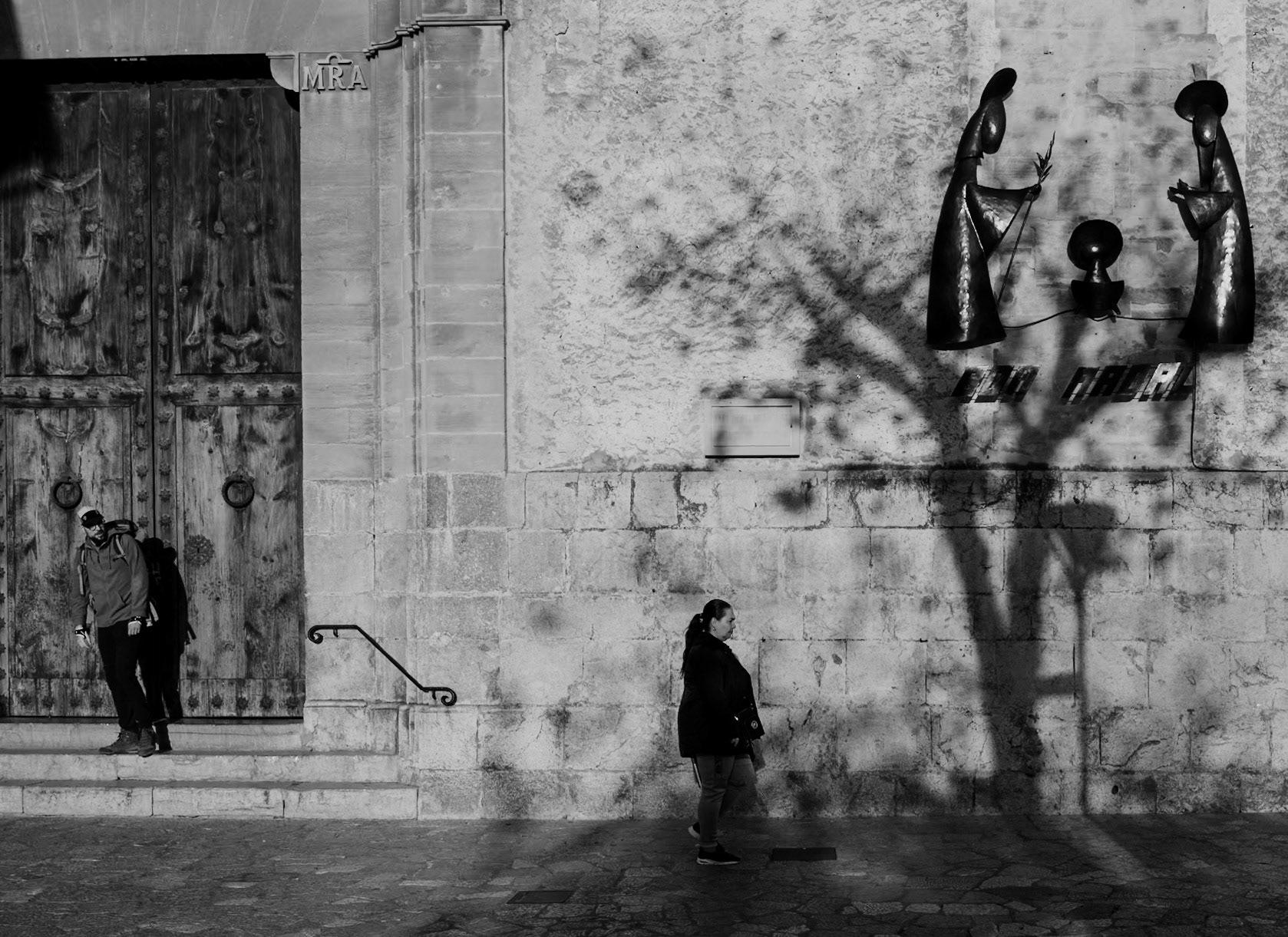 the interplay of shadows and people, both realistic and figurative, occurred at the main church in pollença on a sunday morning in winter.