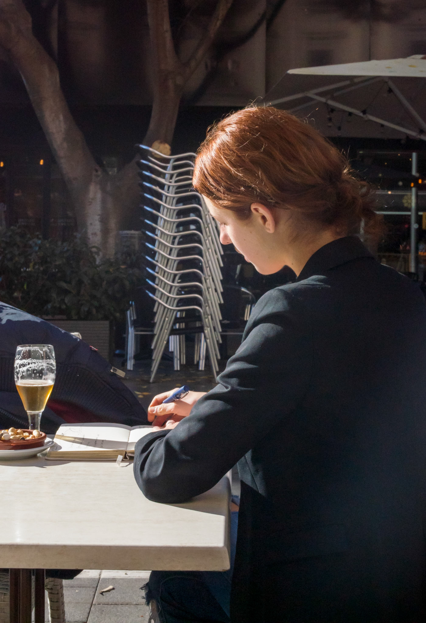 i was surprised by the contrasts and contradictions in this scene.  a young, pretty woman, formally dressed with perfect posture, writing something in an analogue calendar. but drinking a beer with it. when I approached her to ask if I could take her picture, she was polite and friendly. allowed me to photograph her and was not surprised or disturbed by my request but immediately returned to her work very focused. made me curious about whatever could she have been writing?
