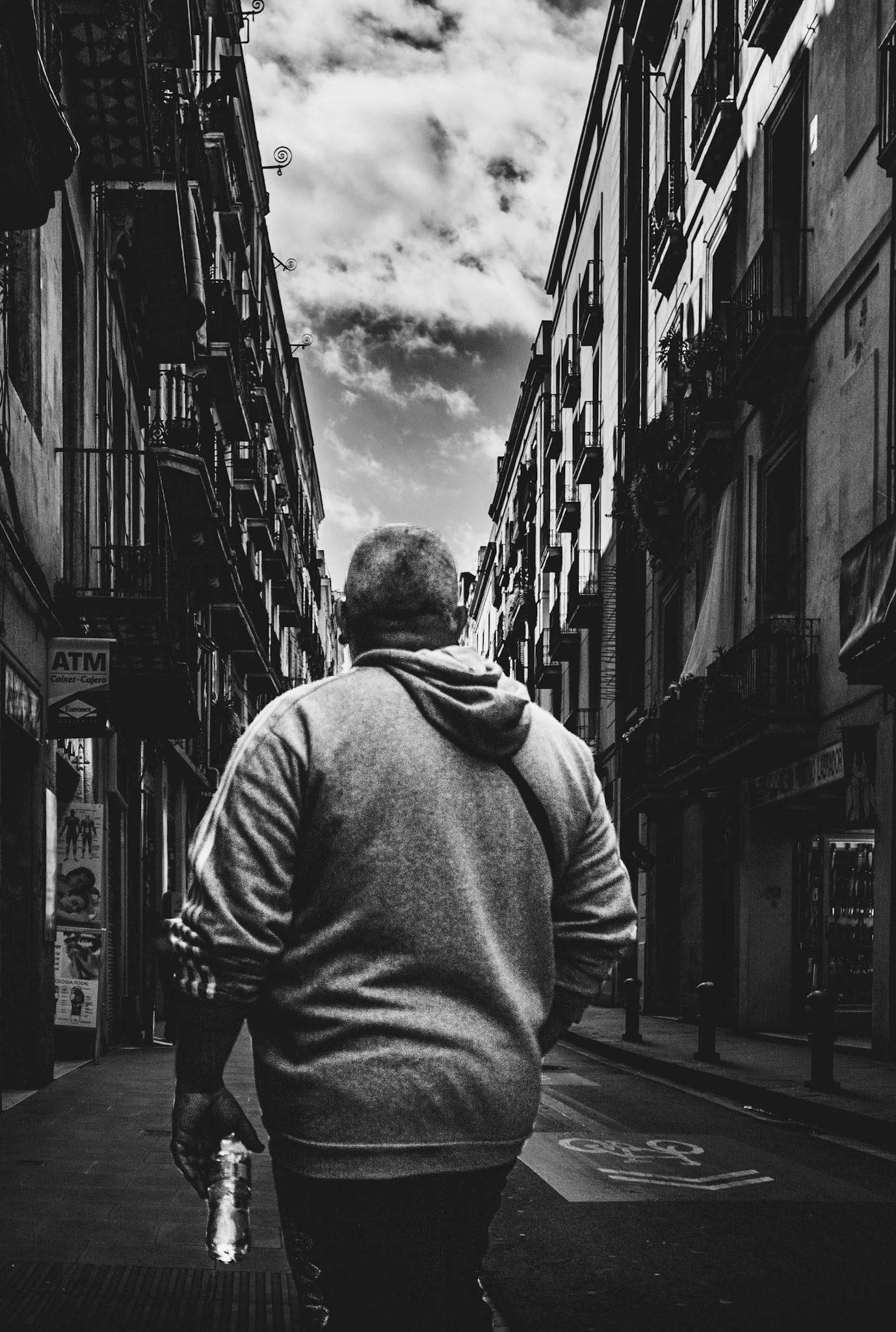 the streets of barcelona tell stories with every step. beneath the heavy skies, a lone figure moves forward, embodying the city's timeless rhythm. the shadows of the narrow alleys grow deeper, and the walls seem to whisper forgotten tales. the contrast between light and dark amplifies the solitude, turning the ordinary into something profound. in the quiet of this moment, it's as if the city itself pauses to breathe.