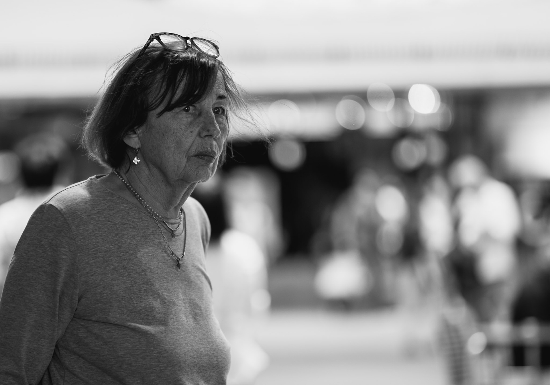 amidst the bustling activity in the heart of the fünf höfe in munich, this woman seems to be finding her way, her expressions mirroring the chaos and liveliness surrounding her. the contrast between her focused demeanor and the blurred, vibrant background captures the essence of street photography in its truest form.captured with a leica m11 monochrom and a noctilux 75mm f/1.25 lens, the image portrays a moment of candid introspection within the urban landscape, highlighting the beauty of everyday life.