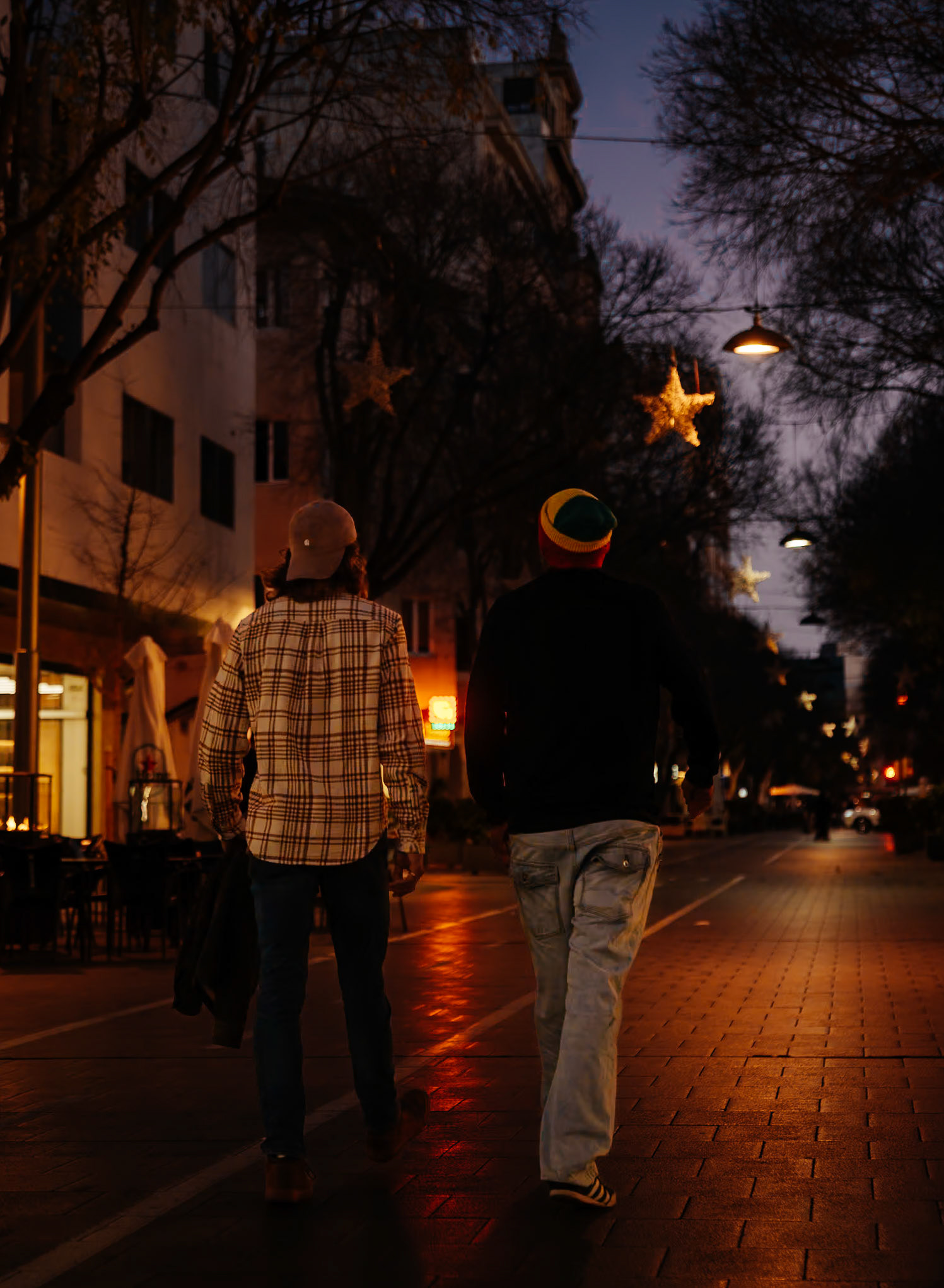 In the quiet evening of Palma de Mallorca, two companions stride along, divided by a serendipitous stroke of light. A reflection casts a vivid red line on the street, a vibrant contrast to the subdued cityscape. It's as if they're walking beside an unseen boundary, a line that shouldn't be crossed, adding a layer of narrative to the urban stroll. The night enfolds the city, yet this single line of color boldly defines a moment shared and a path yet to be chosen.