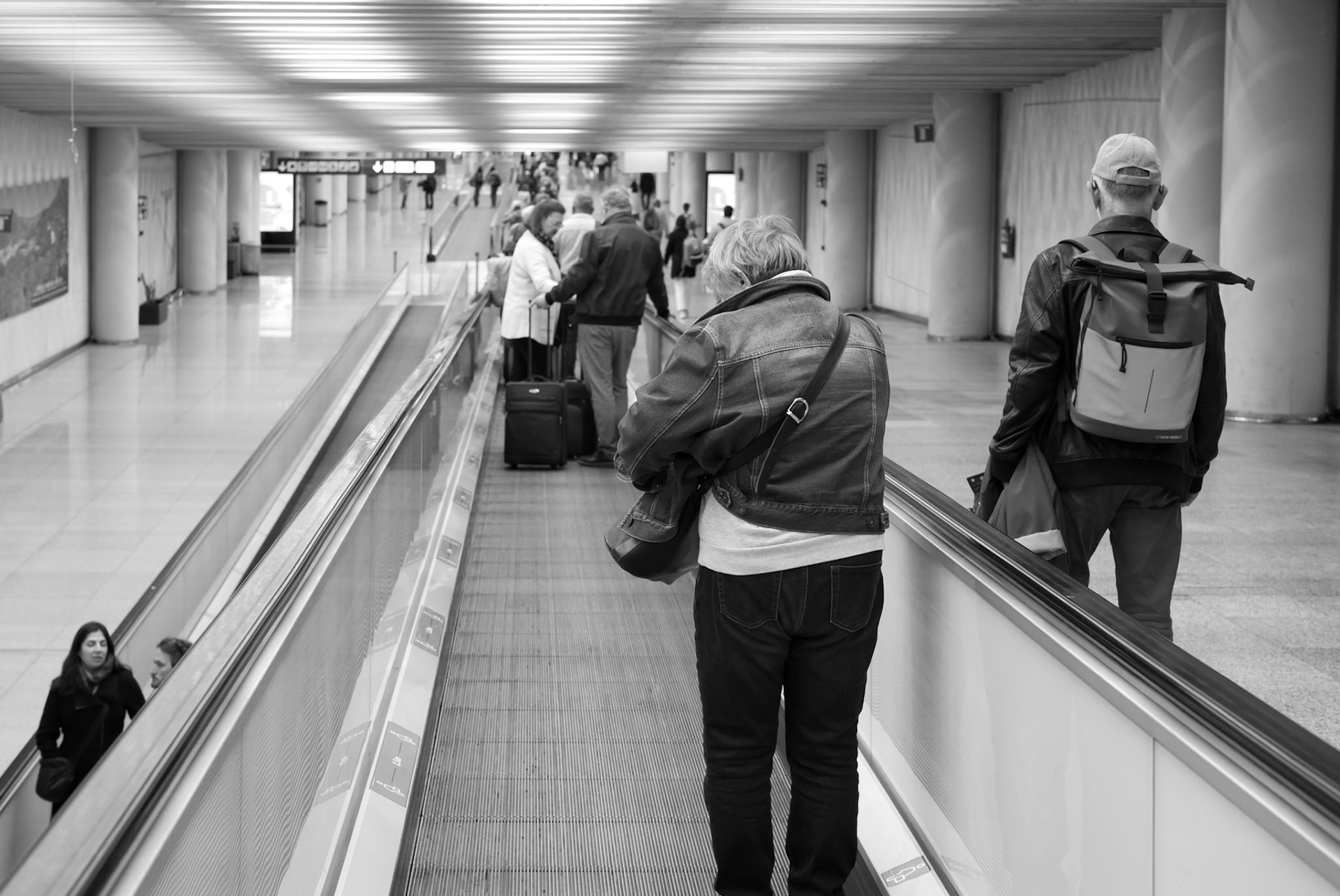 In the subdued bustle of palma de mallorca's airport, a couple finds themselves at a simple crossroad. The woman steps onto the moving walkway, a choice that separates her path from her husband's, who opts for the static ground beside. This ordinary moment captures the essence of travel – paths diverge and align in the flow of journeys. It's a quiet testament to individual choices that define our paths, even when walking side by side. In the background, life at the airport pulses on, indifferent to the tiny decisions that shape our stories.
