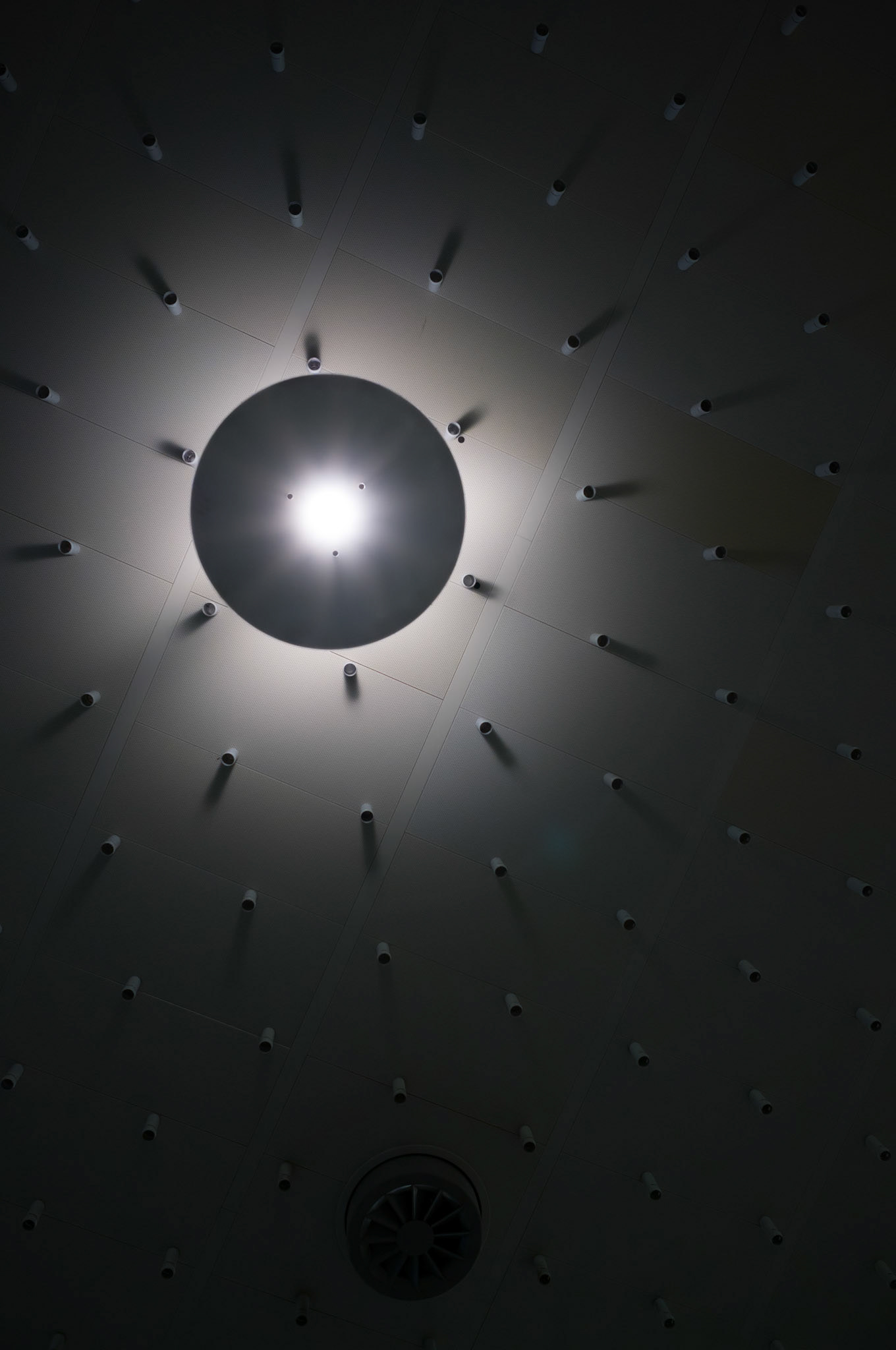 beneath the architectural ballet of hannover's airport, a constellation of ceiling lights casts a geometric dance of shadows and illumination. here, the interplay of light and dark sketches a silent symphony upon the surface, each bulb a soloist in an orchestrated performance of brilliance and contrast. the design, both purposeful and aesthetic, captures the eye, inviting travelers to pause and look upward, to find artistry in the mundane, a moment of beauty amidst the bustle of transit.