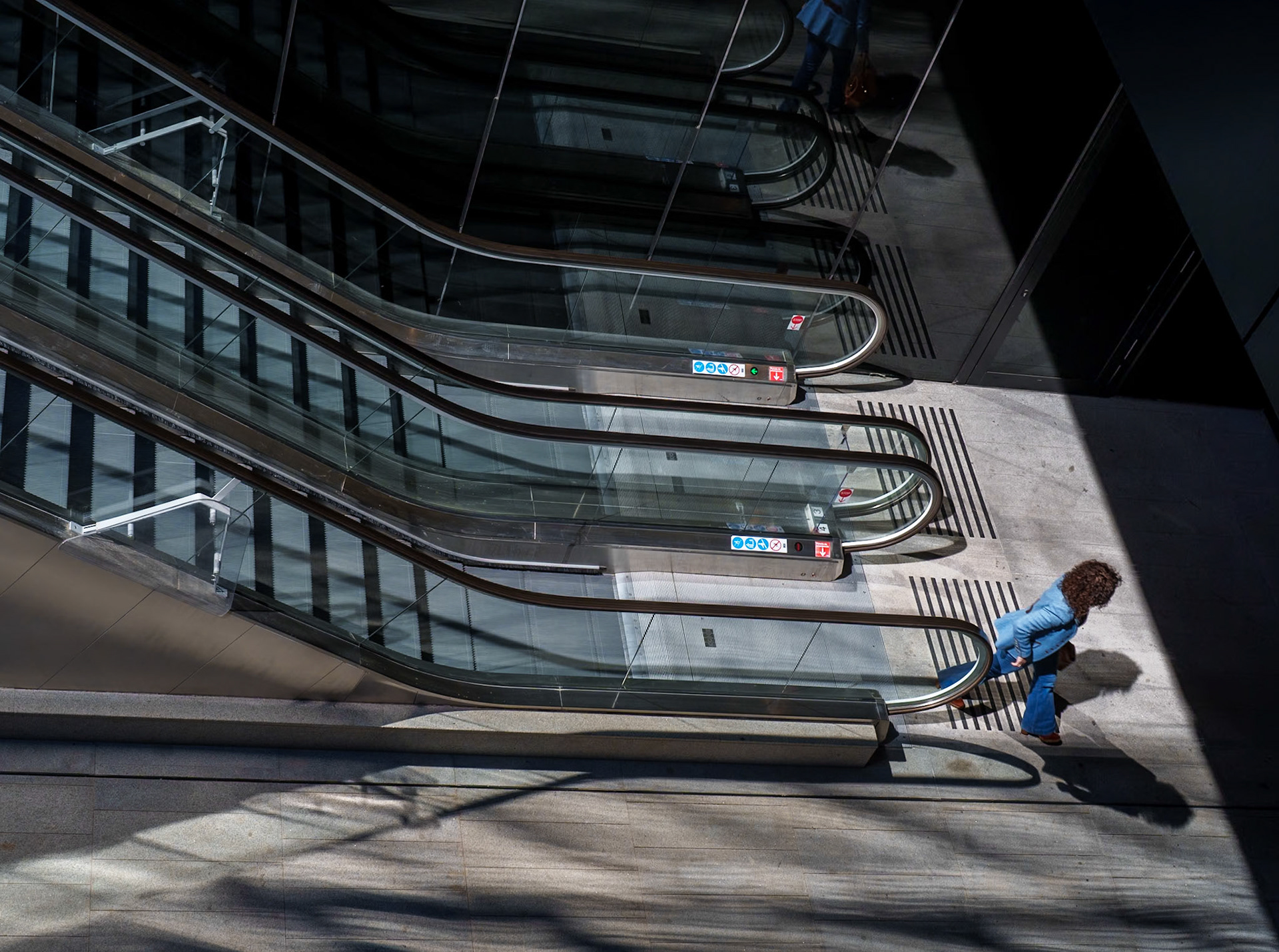 a lone wanderer descends into the belly of madrid, where steel veins pulse against the quiet hum of day. each step is a silent beat in the symphony of routine, the escalators a bridge between realms. shadows carve out spaces forgotten by the sun, and light slices through the gloom, a reminder that even in the depths, paths lead onward.