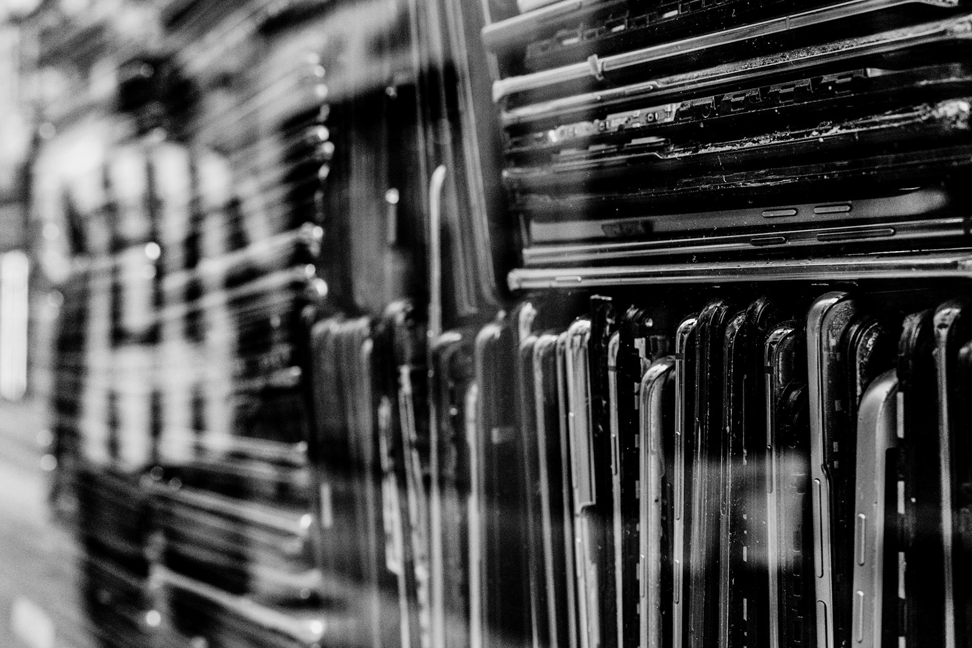 in the heart of palma de mallorca's old town, this photograph captures the storefront of a phone repair shop. as a quirky display, old and broken phones are stacked high in the window, creating a visually chaotic yet intriguingly patterned scene. the arrangement of these discarded devices forms lines that stand in stark contrast to the reflection of a passerby in a jersey, adding a layer of dynamic interaction between the structured chaos and the life outside.