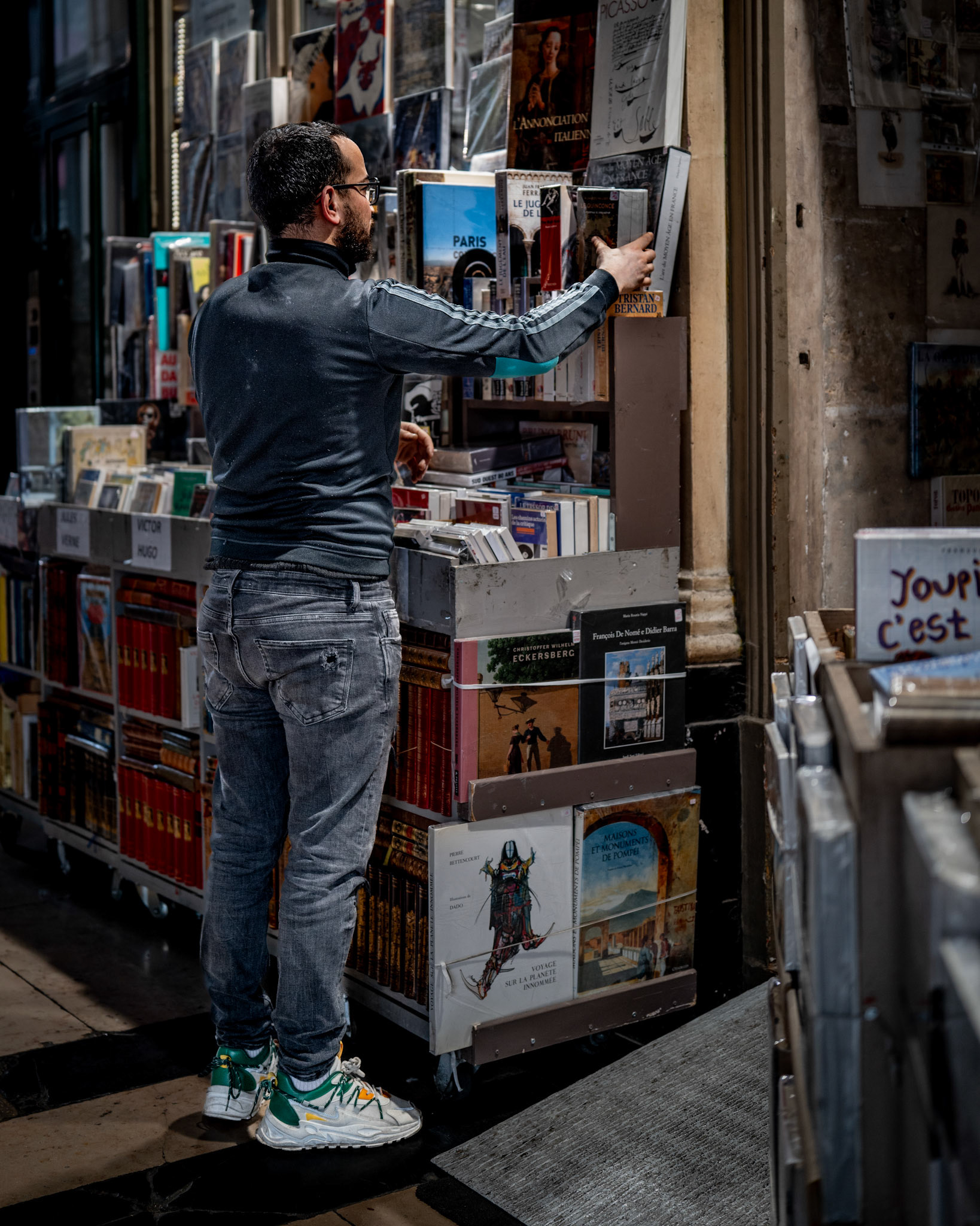 in the heart of montmartre, there’s always time to lose yourself in a good book. as the evening settles in and the streetlights flicker on, this man stands quietly surrounded by stories. the rows of books seem to whisper secrets of the city’s soul, capturing the magic of montmartre in this one, fleeting moment. the warm lights of paris reflect off the shelves, inviting passersby to stop and explore a world bound by pages.