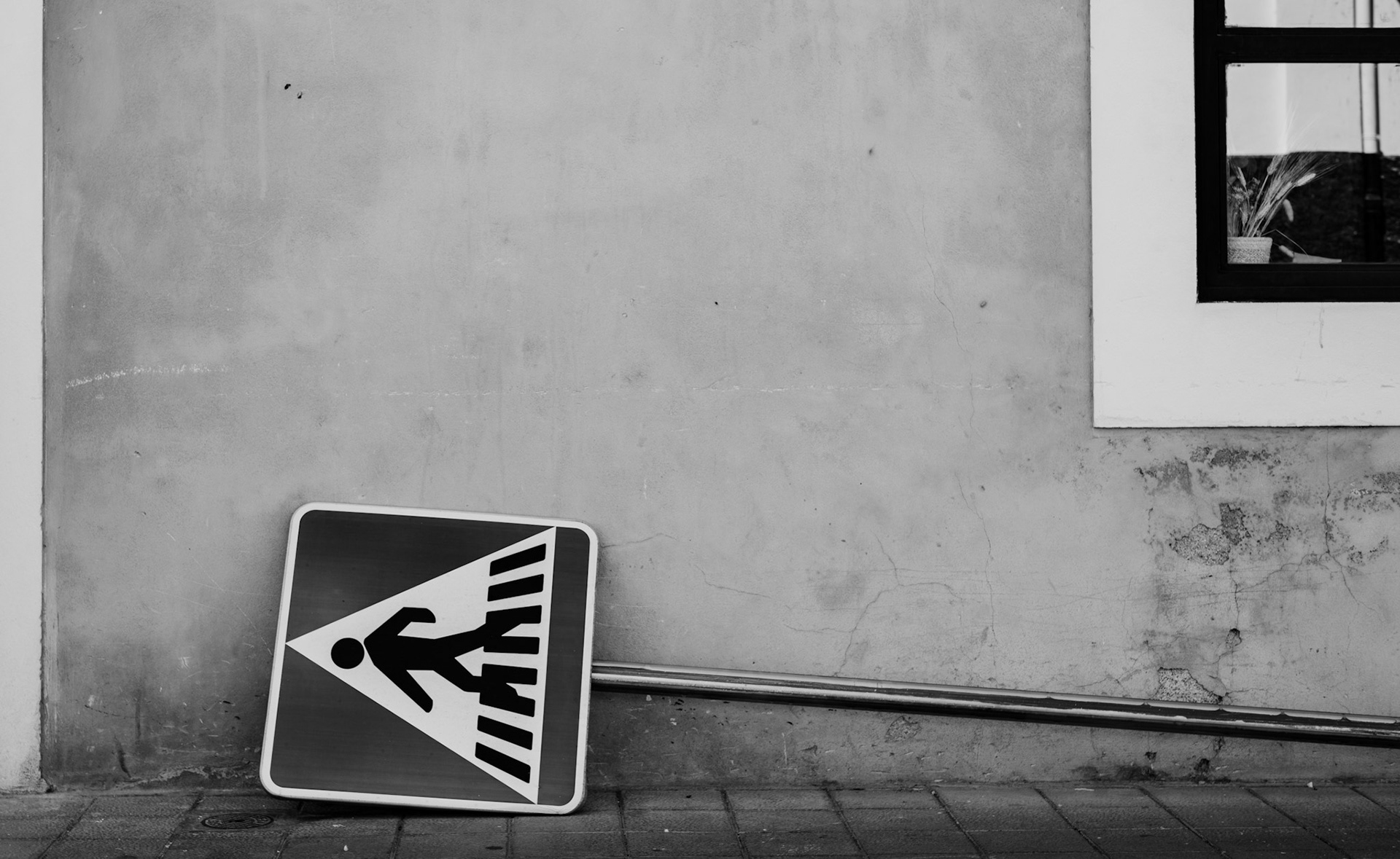 in the heart of santa catalina, a pedestrian sign lies abandoned against a weathered wall. the stark black and white of the image amplifies the sign's loneliness, hinting at the countless stories that pass by unnoticed in this vibrant district. the tilted sign, meant to guide and protect, now rests in disarray, reflecting the fragility of order in urban life. this scene, captured in a moment of quiet neglect, speaks volumes about the unnoticed and overlooked elements that still play a role in the rhythm of the city.