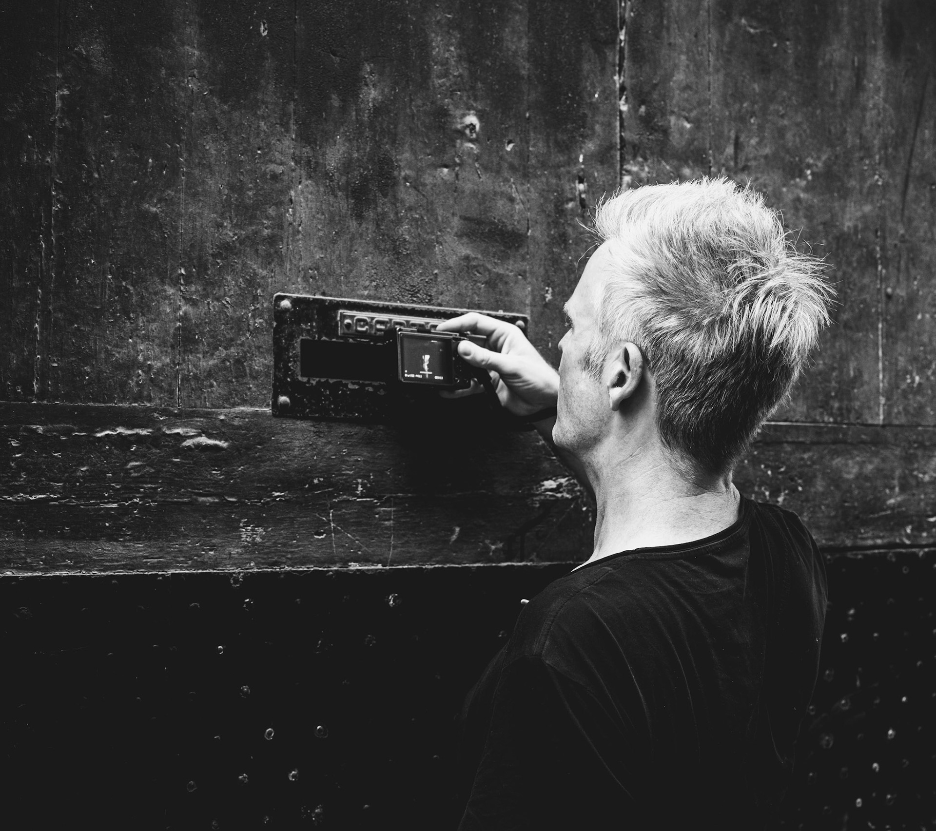 on a warm day in palma, amidst the bustling streets, thomas and i embarked on a photo walk, discovering the hidden narratives of the city. thomas, with his incredible eye for detail, paused by a weathered door, intrigued by what lay beyond. his camera captured the essence of curiosity as he peered through a mail slot, uncovering the stories concealed within the shadows. this moment, frozen in black and white, embodies the timeless allure of street photography—finding beauty and intrigue in the ordinary.
