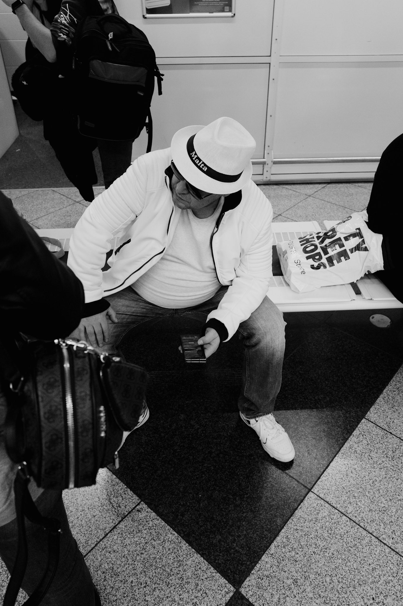 in the bustling expanse of munich's airport, amid the hum of arrivals and the anticipation of reunions, there lies a quiet symmetry. here, in the luggage claim hall, a traveler's stride is silently echoed in the polished gleam of the floor—a momentary twin birthed from light and shadow. this monochromatic frame captures more than a mere reflection; it's a dance of movement and stillness, a visual pause in the narrative of transit, where each person's passage is briefly, beautifully doubled.