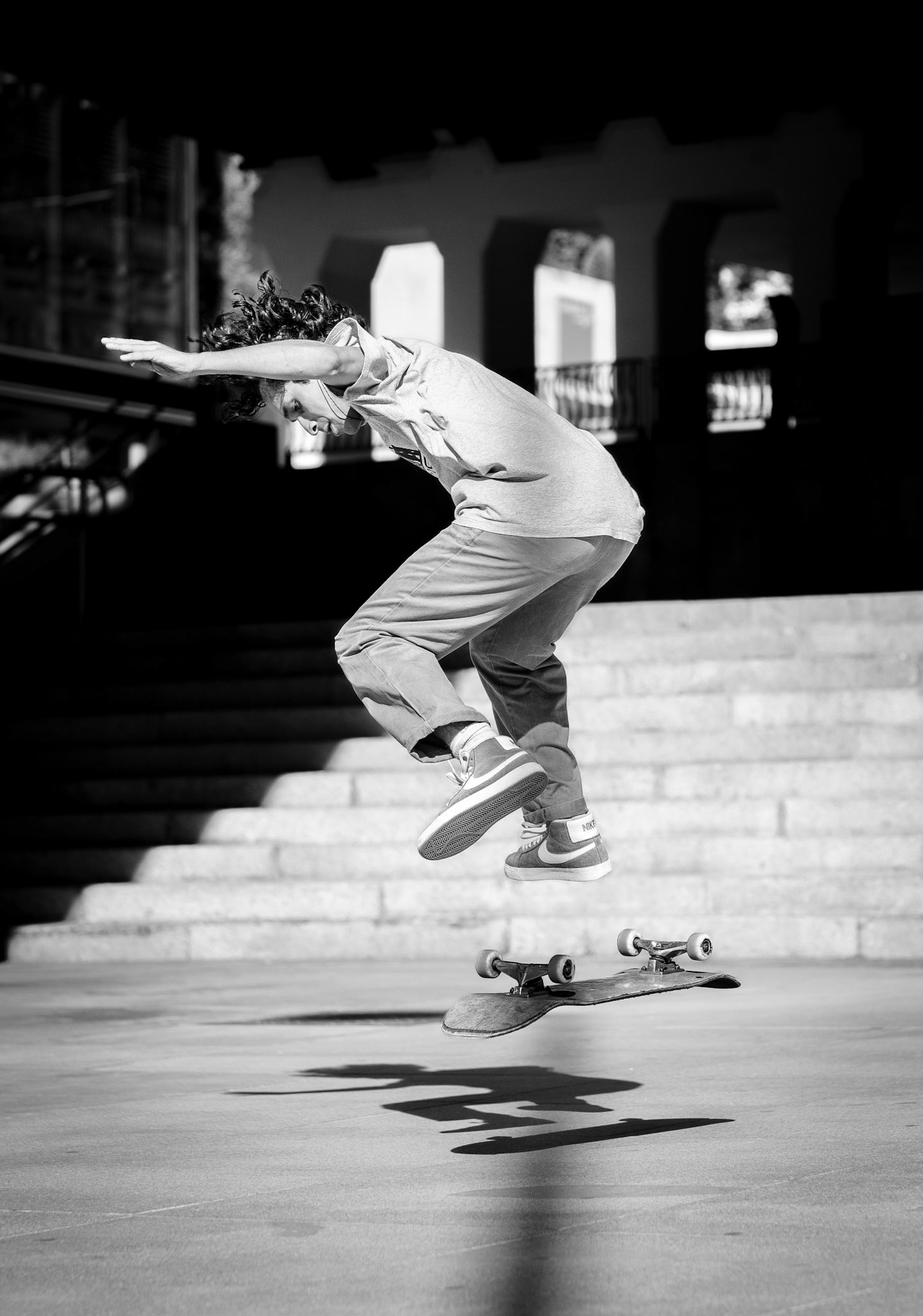 captured at plaza escultor juan de ávalos in madrid, this photo freezes a perfect skateboarding moment – a split second between ground and air, gravity and weightlessness. the black-and-white palette emphasizes the graphic power of the jump, drawing attention to the silhouette of the skater and the hovering skateboard. the sharp shadows on the ground mirror the fluid motion and add an extra dimension to the image. the dark, empty background intensifies the sense of isolated energy and pure focus. in this suspended instant, everything seems to stand still – a tribute to the art of skating and those moments where everything feels just right.