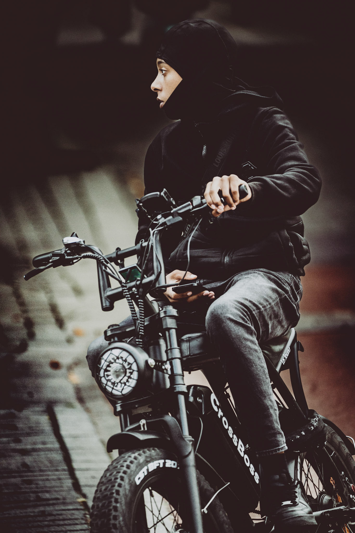 as i wandered through amsterdam's streets, i spotted this figure—swift yet steady, deep in thought, the city moving with him. his dark attire melts into the overcast atmosphere, but there's a quiet resilience in his glance. it's a moment of contrast: the soft urban haze, the hard edges of his bike, and that fleeting second of introspection.