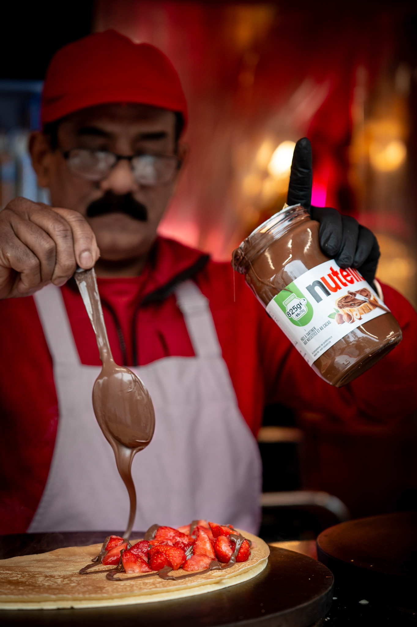 sitting quietly at a food stall in paris, you witness a culinary contradiction—a crêpe, a symbol of French simplicity and at the same time rafinesse, adorned with strawberries and dripping in nutella. the soft layers, meant to be enjoyed with minimal ingredients, now transformed into a dessert spectacle. the photo captures this moment of indulgence, questioning the necessity of such excess, where tradition meets the whims of modern taste.