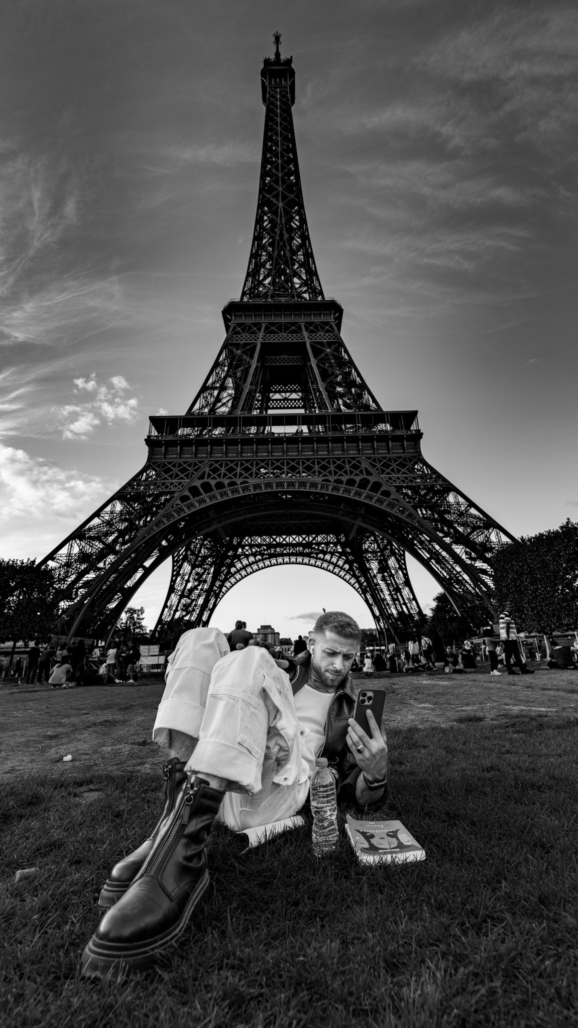 it was one of those moments where the eiffel tower seemed less about the iconic symbol it represents, and more of a casual backdrop to the daily life around it. he lounged on the grass, phone in hand, fully immersed in his screen, while the iron giant towered overhead. the contrast between the timeless structure and his focus on something so modern brought a quiet balance to the scene. this image isn’t about the eiffel tower, but about how it becomes part of everyday life for those who pass beneath it. a perfect blend of past and present.