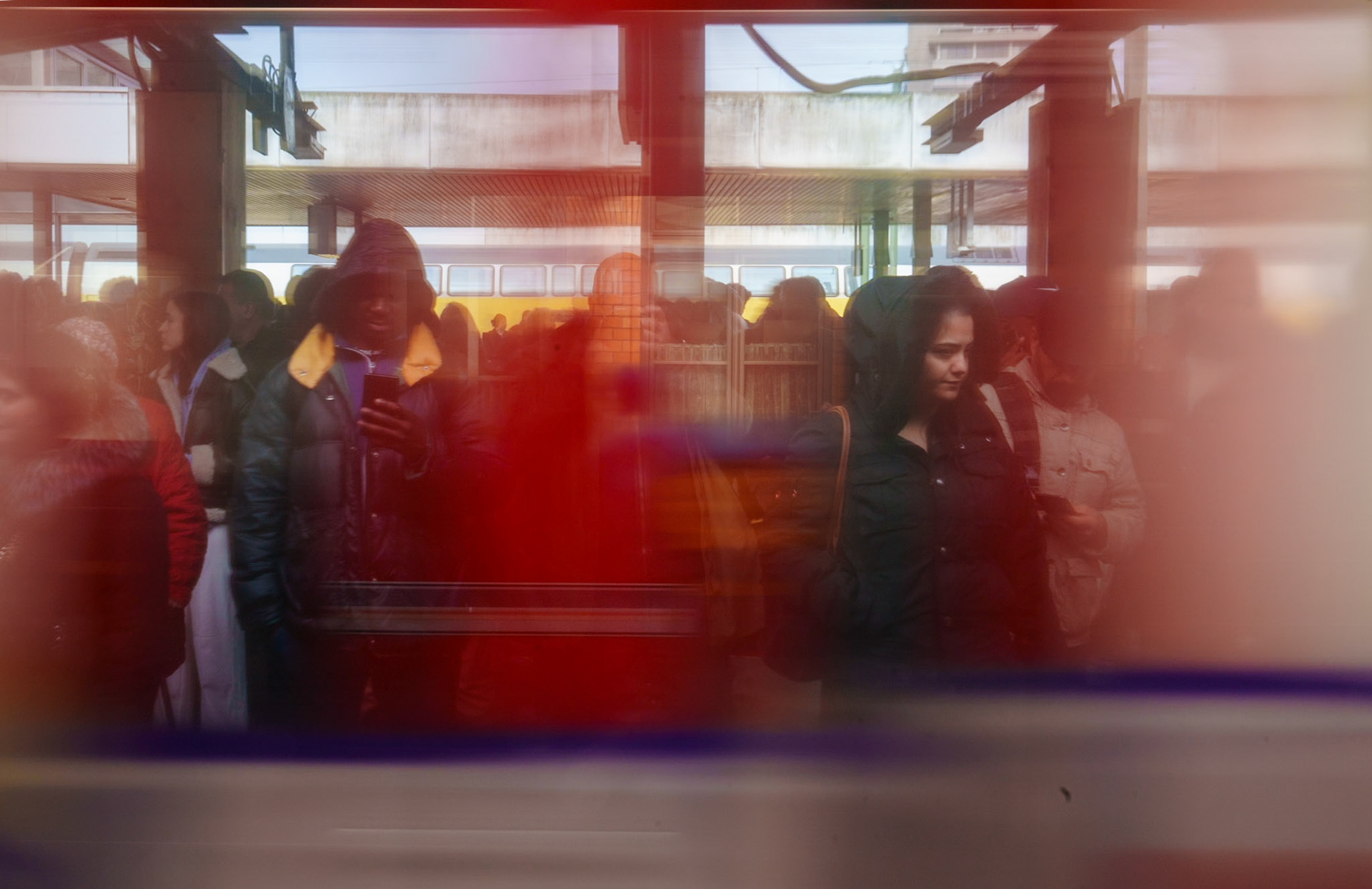 hannover central station, a nexus where countless stories intersect. through a kaleidoscope of reflections, life unfolds in layers. a moment, fleeting yet full, as strangers share a platform, each absorbed in their own world. the cold bite of the morning air contrasts with the warmth that lingers behind the glass. colors blur, a vivid streak across the canvas of daily commute. here, a figure stands out, cloaked in contemplation, their gaze fixed on a destination unseen. another, a silhouette against the morning rush, finds solace in the sanctuary of her thoughts. this image, a snapshot of transient solitude amidst the communal rhythm of travel, captures the quiet intimacy of public spaces, where every passerby is a story, every reflection a window into another life.