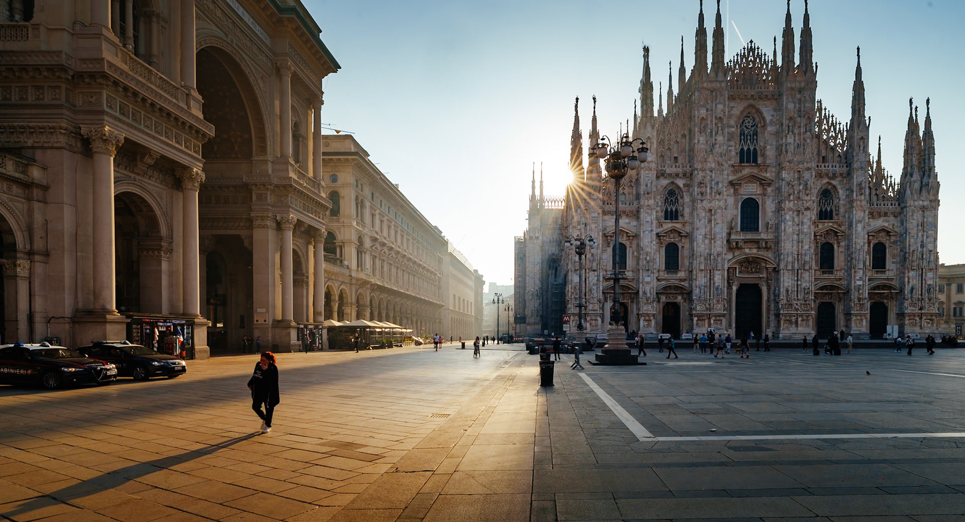 as dawn's first light washes over milan's duomo square, the day begins with a quiet splendor. the sun, peeking through the spires of the grand cathedral, casts a golden glow that glistens on the stones of the piazza. the shadows are long, the air is still, and the city breathes in the tranquility of the morning. pedestrians, small figures in the vast expanse, tread softly across the square, their movements as gentle whispers against the magnificence of history etched in the duomo's facade. this is a place where every sunrise feels like the first, a timeless scene in a city ever moving forward.