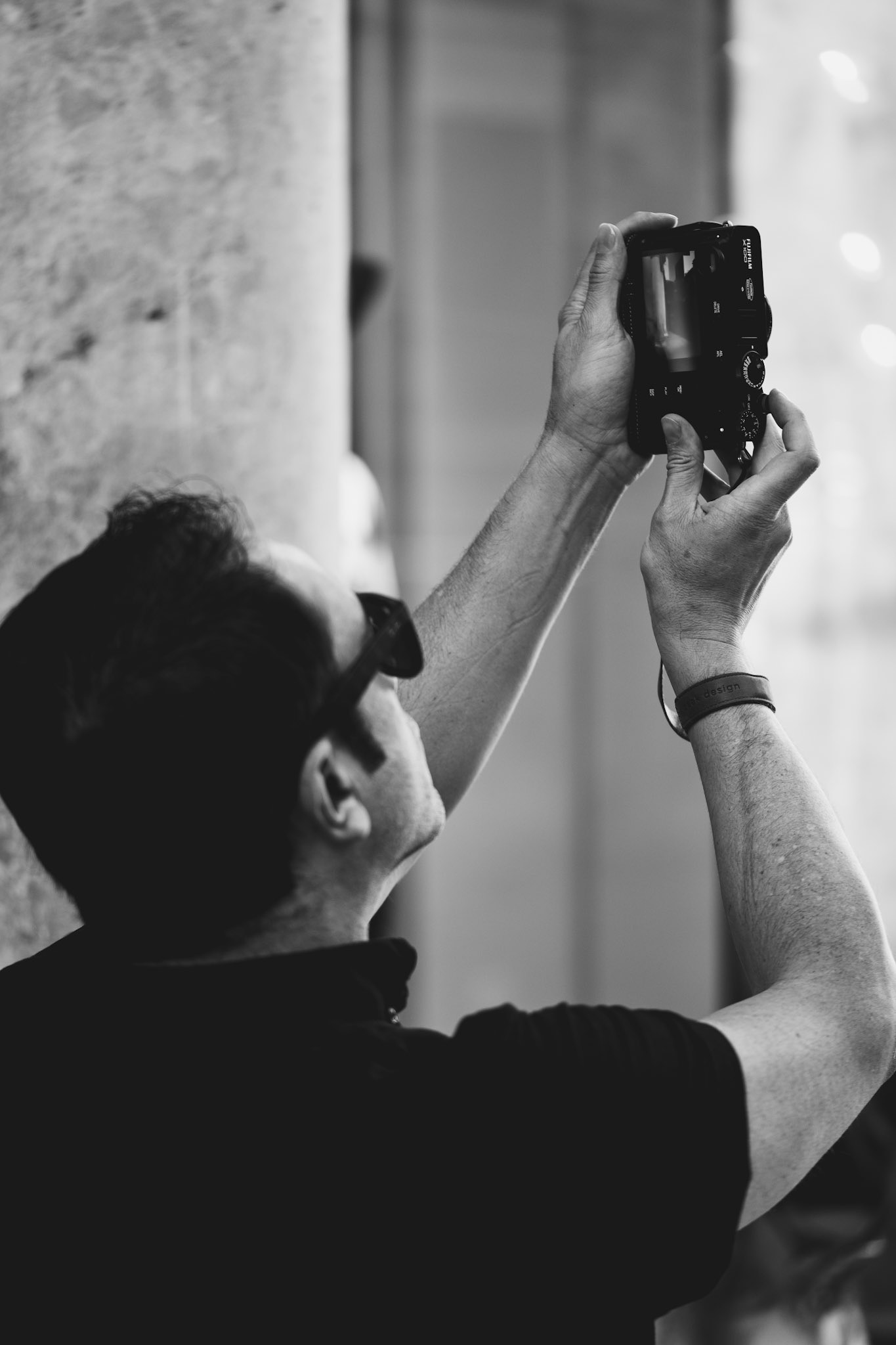 captured during a photowalk in palma, this photograph depicts another photographer engrossed in capturing the historic facades bathed in the warm light of the late afternoon. the concentration and dedication are palpable, as his camera frames the timeless beauty of the city's architecture. this scene, caught in black and white, underscores the passion and art of photography, where each moment is meticulously framed and preserved.