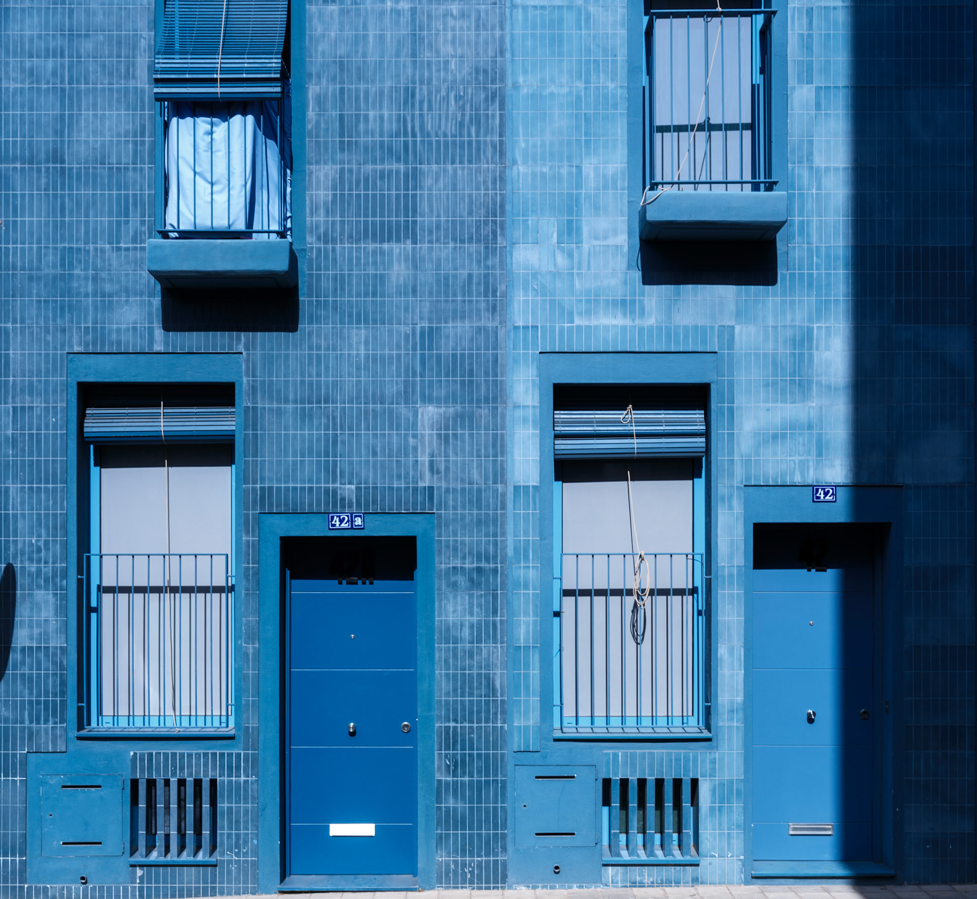in the heart of avenida joan miro, where the pulse of palma de mallorca beats in a rhythm painted in hues of serenity, stand the echoes of eight houses – a chorus in blue. each facade, a stanza of its own, sings a variation of azure, as if the sky had whispered secrets into the architect's ear. the firm gras has spun a thread of continuity with each shade, crafting a visual melody that plays upon the eyes and calms the urban clamor. here, the sun casts geometric poems on the walls, a play of light and shadow that dances till dusk. in this moment captured, the ordinary is suspended, inviting passersby to ponder the artistry of variegated blues, the symphony of simplicity in this residential cadence.