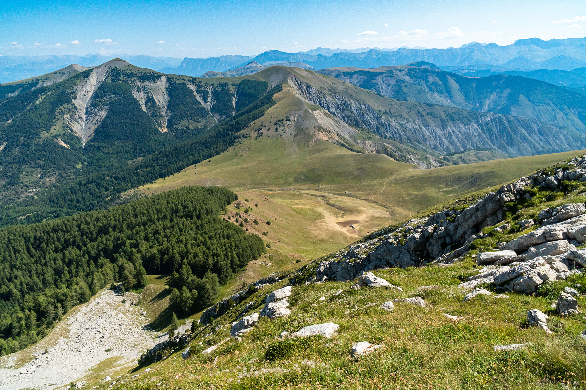 La cabane de Clapouse sur le chemin des sommets du massif des Monges, depuis le sommet des Monges, puis les sommets de la Laupie, du Clôt Ginoux ou les Cimettes, de l'Oratoire, de la Chanau, finissant à Tête Grosse à Selonnet (Chabanon). Au loin les promontoires du Morgon et de Dormillouse encadrant la branche Ubaye du lac de Serre-Ponçon.