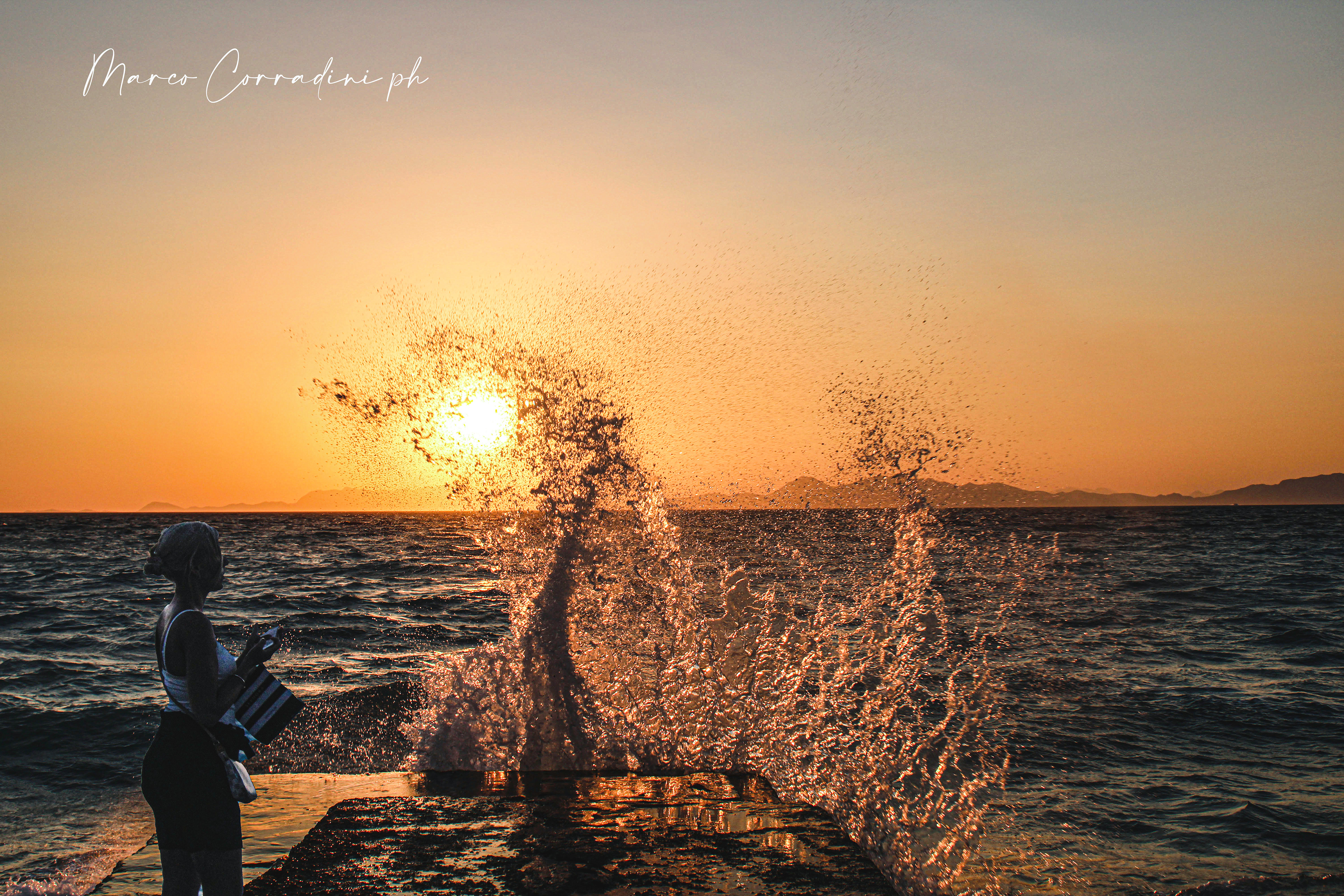 Girl observes wave at sunset in Rhodes