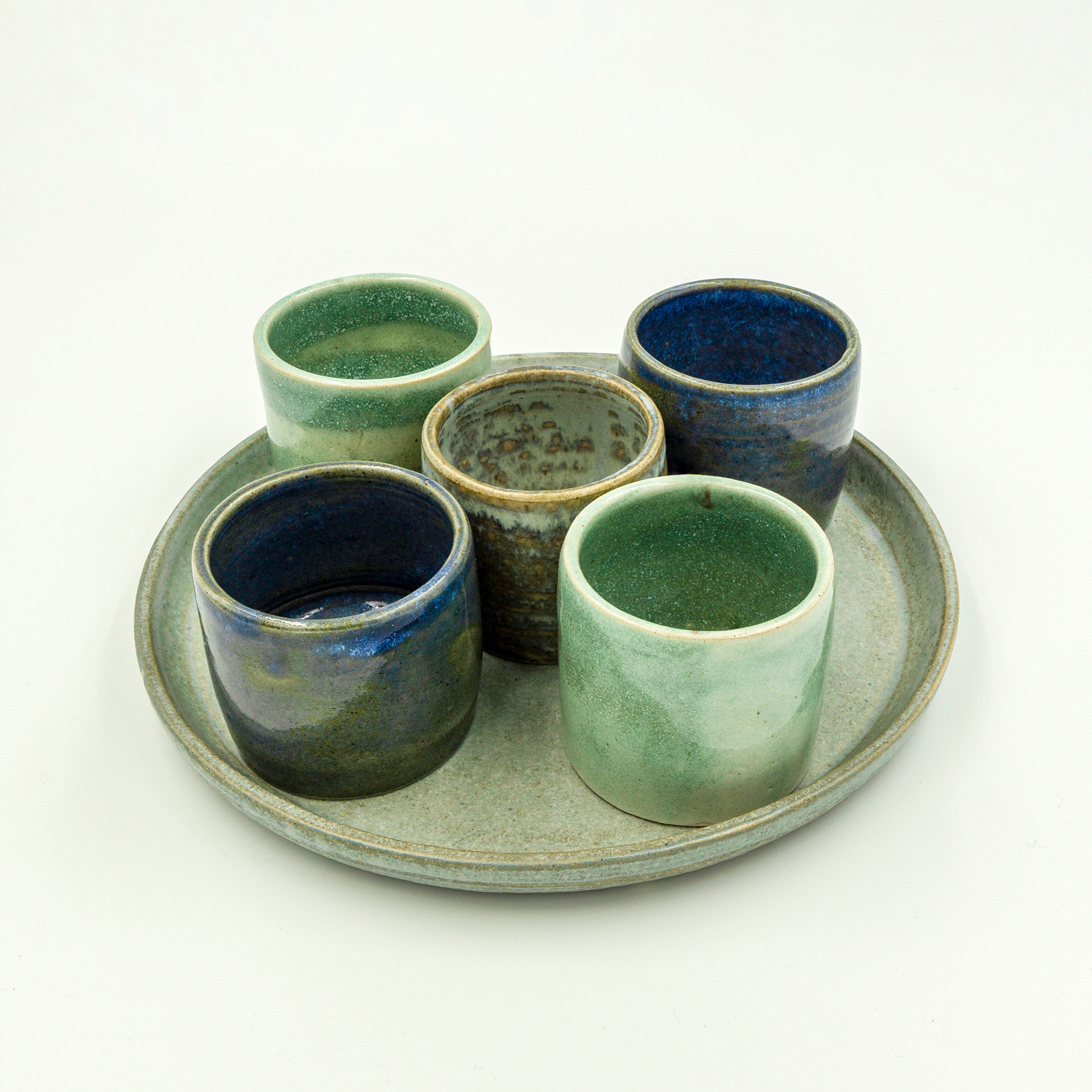 Five espresso cups and a plate in various glazes