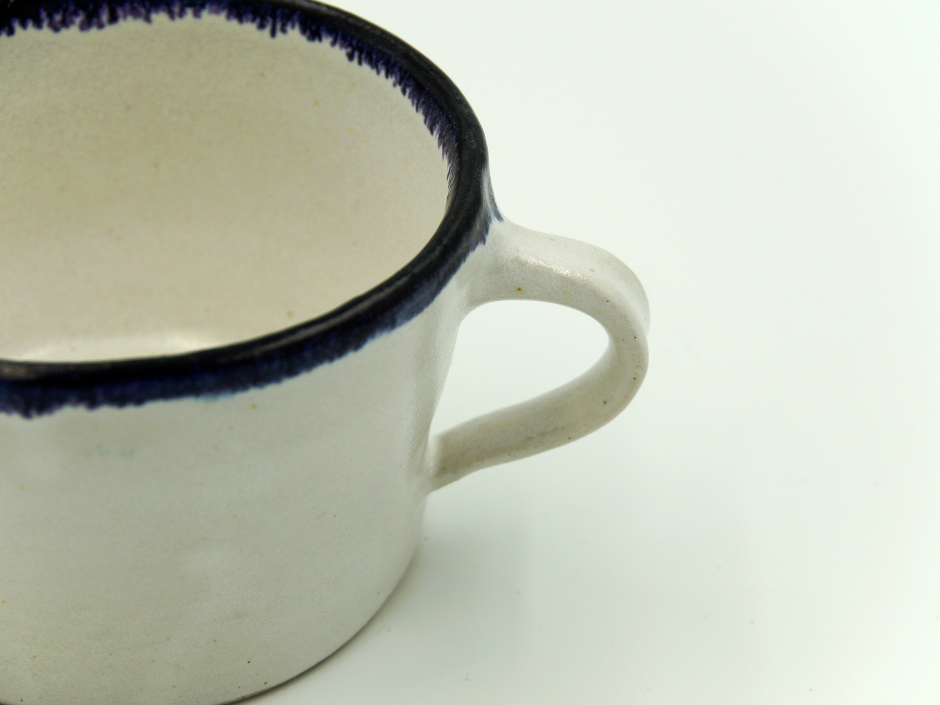 One of a set of cups in satin white glaze with blue oxide rim
