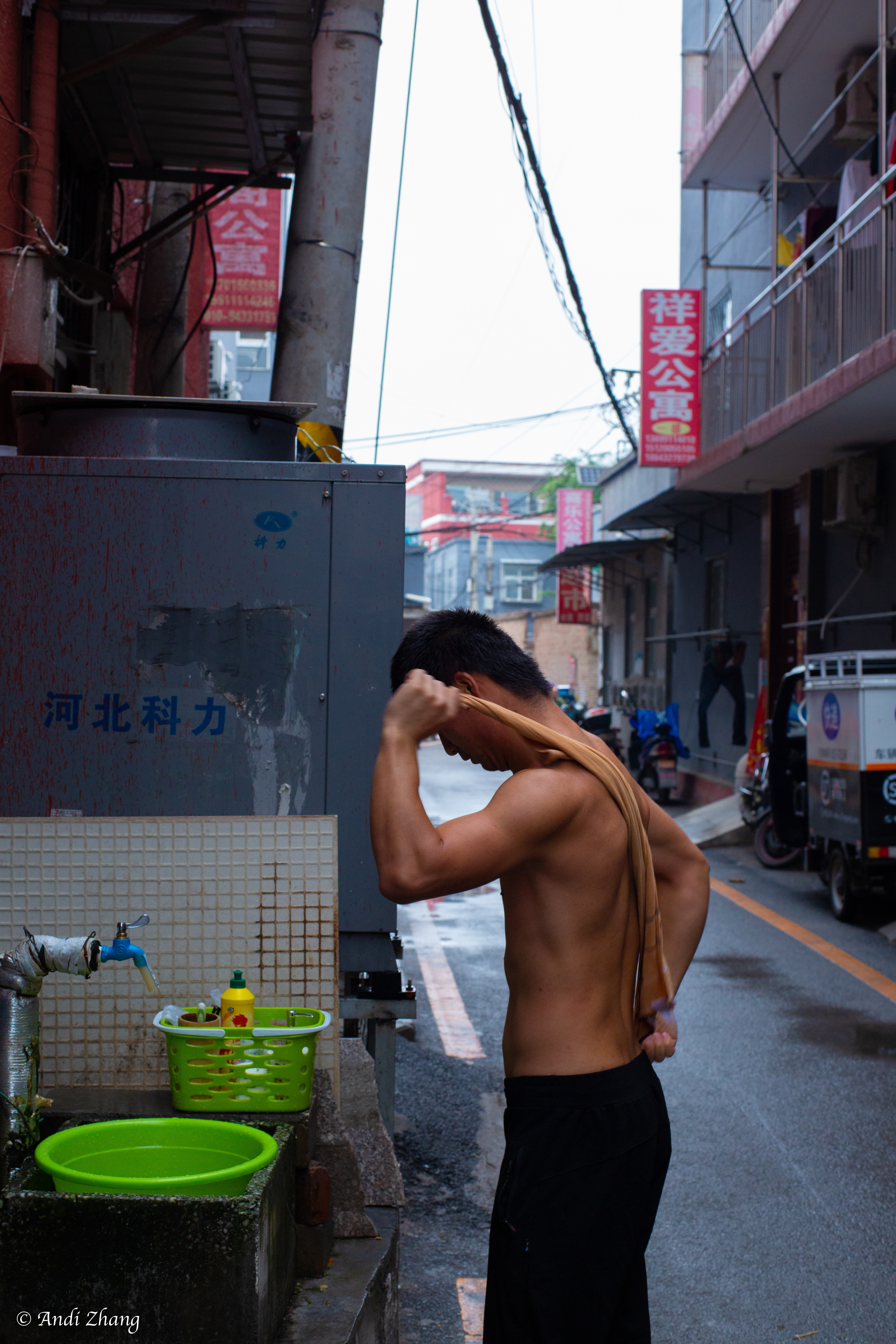 Outside an apartment building, a young man is taking a bath by the road. September 14, 2020.
