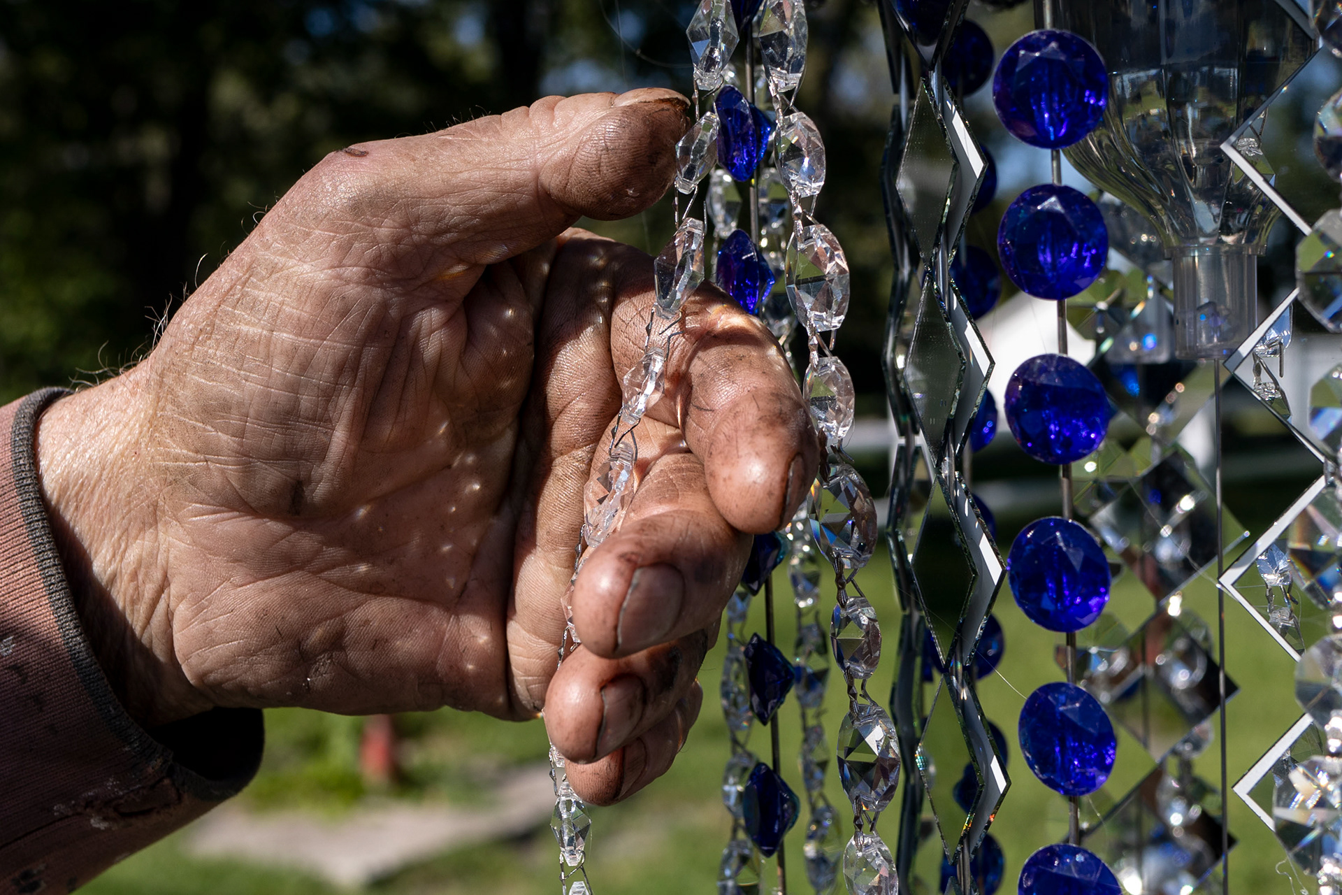 Bill Moore, runs his hands through decorative mobiles made of metal and glass in Stony Ridge, Ohio on Wednesday September 29, 2021. 