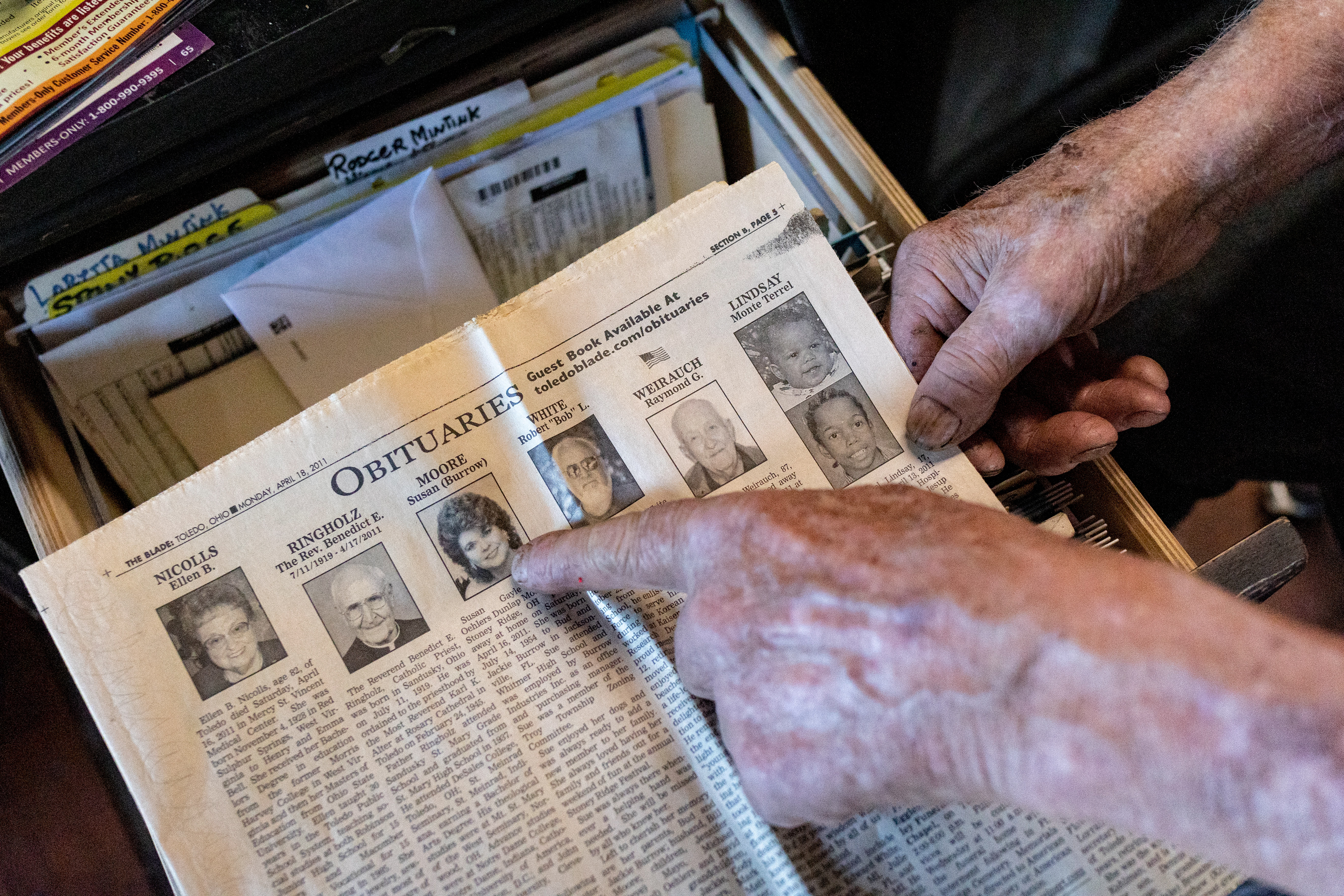 Bill Moore pulls out The Toledo Blade paper that had his wife’s obituary in it back in April of 2011 in his house in Stony Ridge, Ohio on September 29, 2021. Moore recounted, “She died right next to me in bed.”