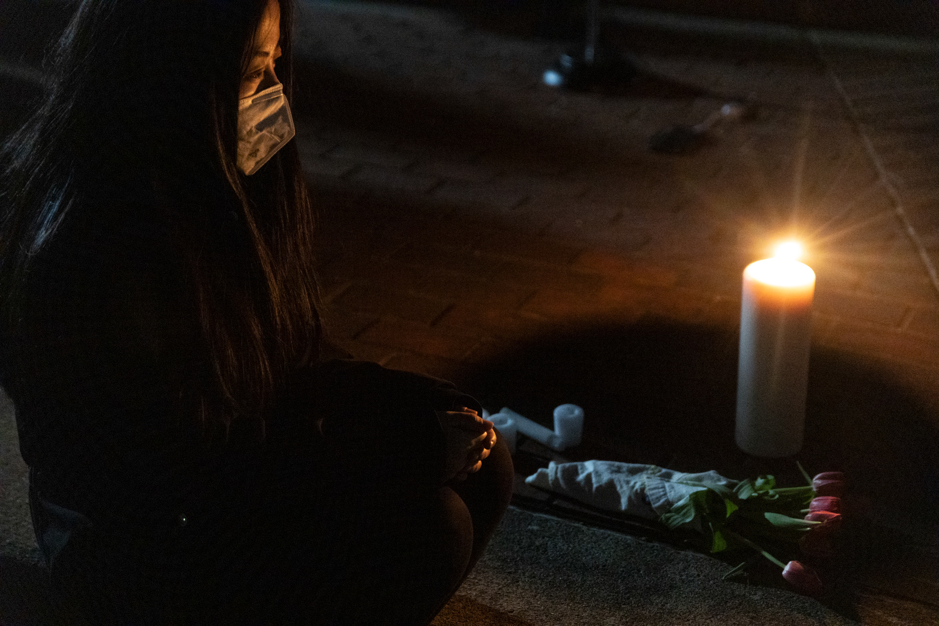 An attendee of a “Stop Asian Hate” vigil, who preferred to remain anonymous, kneels in front of a candle and flowers in memory of those who were killed in the shooting in Atlanta, Georgia the previous Tuesday in Columbus, Ohio on Saturday March 20, 2021. The Filipino activist group Anakbayan organized the event in reaction to the Atlanta shooting as a safe space to talk about Asian experiences of racism, how to get involved in activism and culminated with a candlelight vigil for the victims of the shooting that happened this past Tuesday March 16, 2021 in Atlanta, Georgia. 