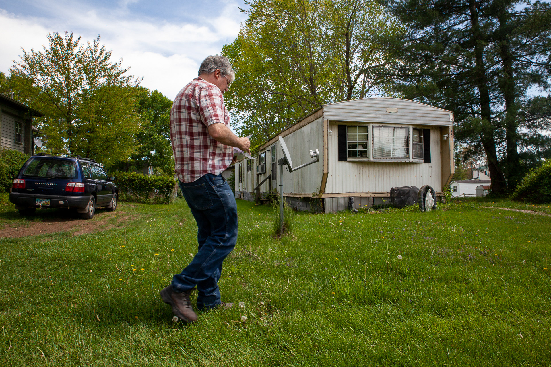 Christopher Ewing, picks up the mail, consisting of bills he is unsure he will be able to pay. "They always send me this letter on a Sunday," says Ewing who is afraid he may have his possessions, his home, and his car taken away from him.