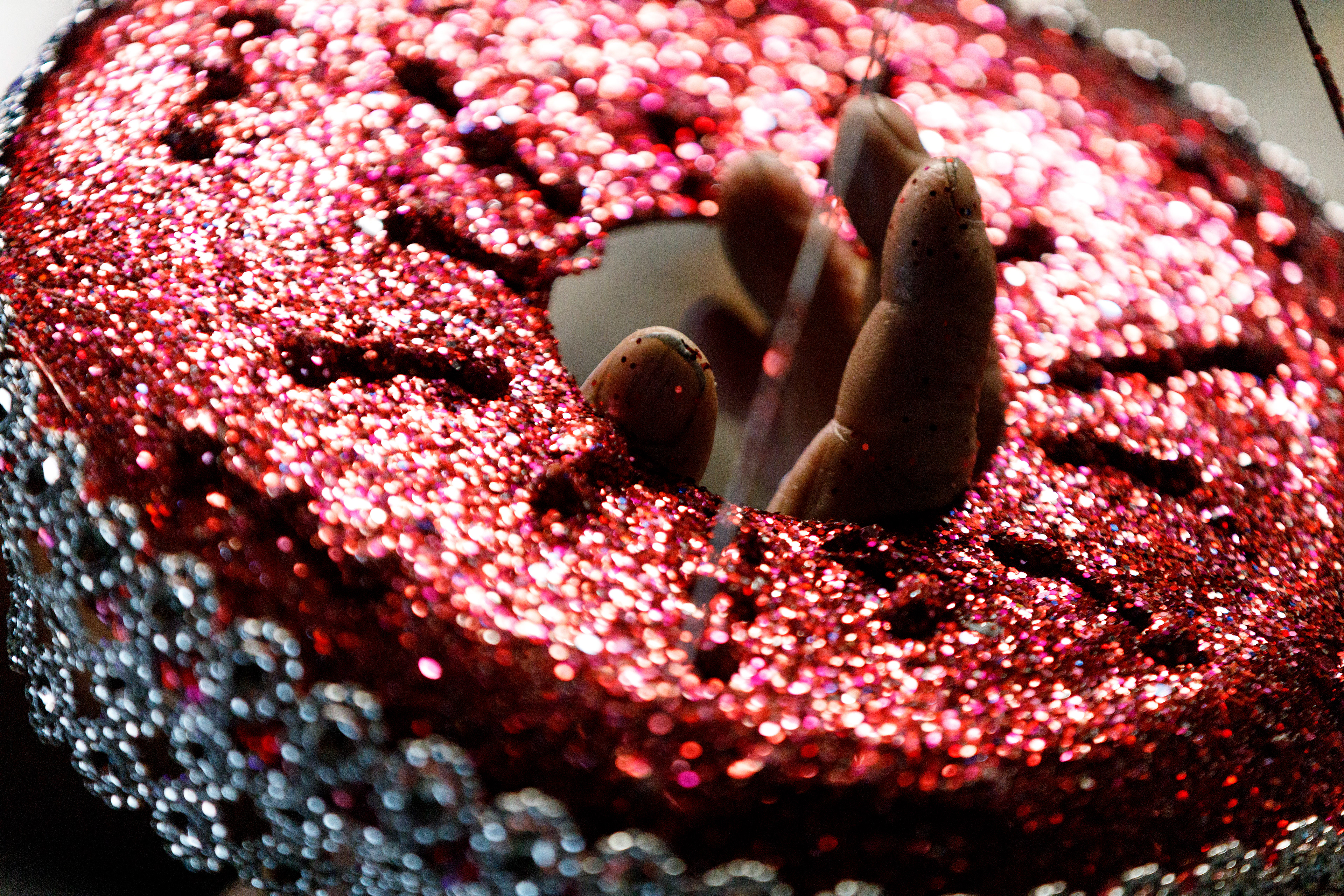 Bill Moore holds a decoration still, while he glues different beads and glass to the outside of it in his home in Stony Ridge on Wednesday October 13, 2021.