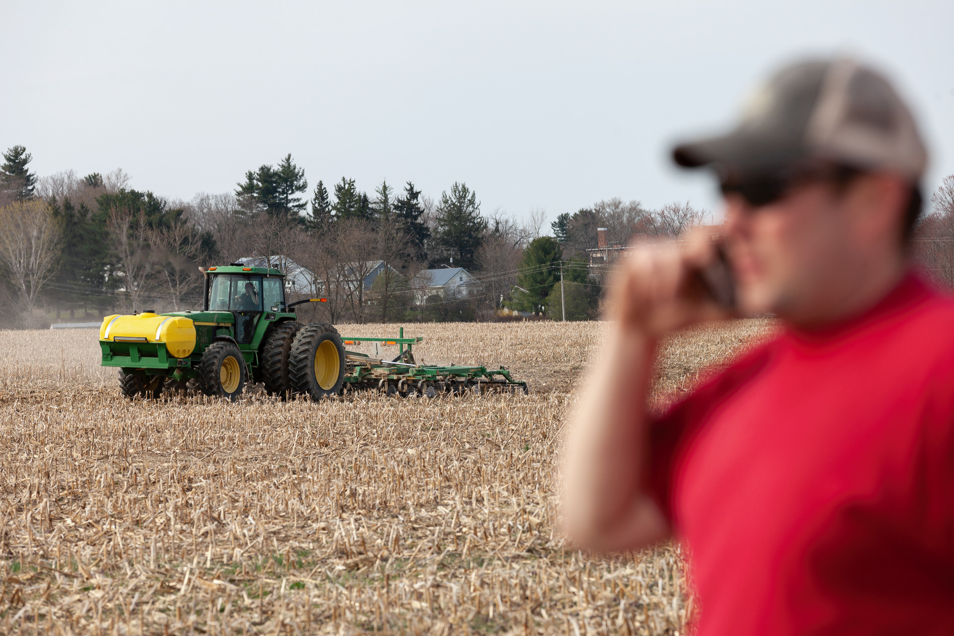 Eric Cotterill, 31, of Albany, Ohio, communicates with his father, Jeff Cotterill, 56, of Albany, Ohio, over the phone on location, while his father tills soil from one of the sites that they rent for their farm, Apr. 4, 2019. In Albany, the Cotterills are forced to rent more land to try to move a profit, when it comes to farming.