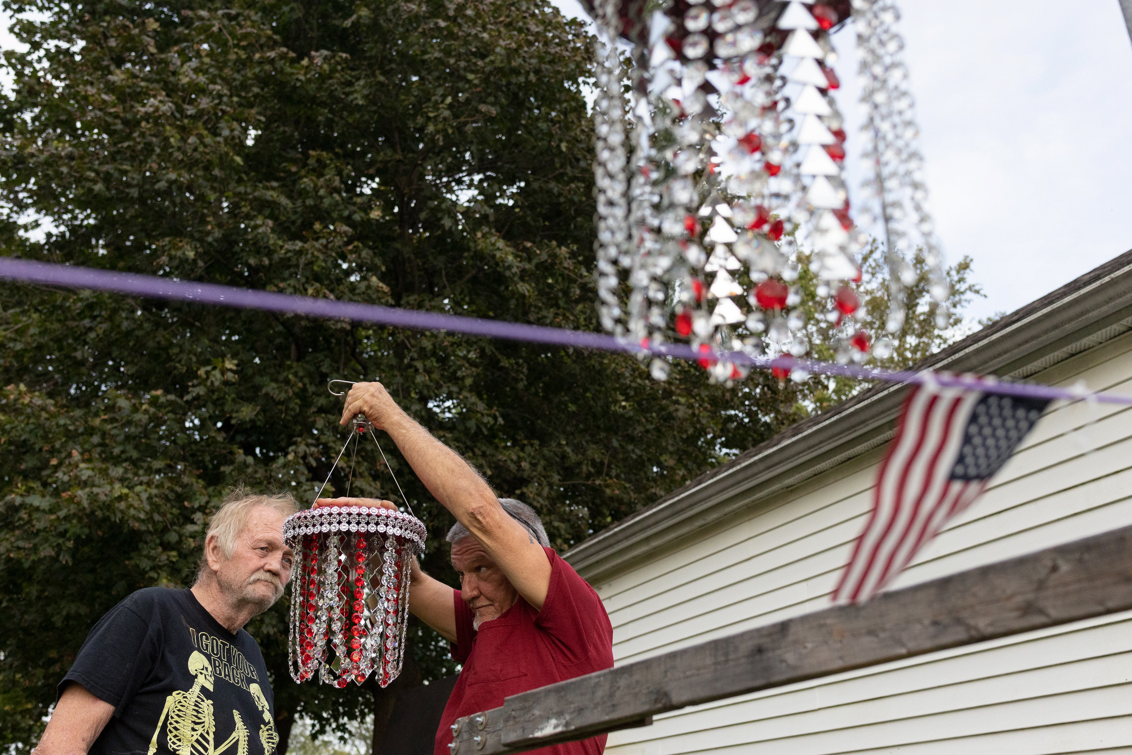 Roger Cox, one of Bill Moore’s friends, holds one of Moore’s decorations, and looks to see it reflect in the sunlight in Stony Ridge on Wednesday October 13, 2021.
