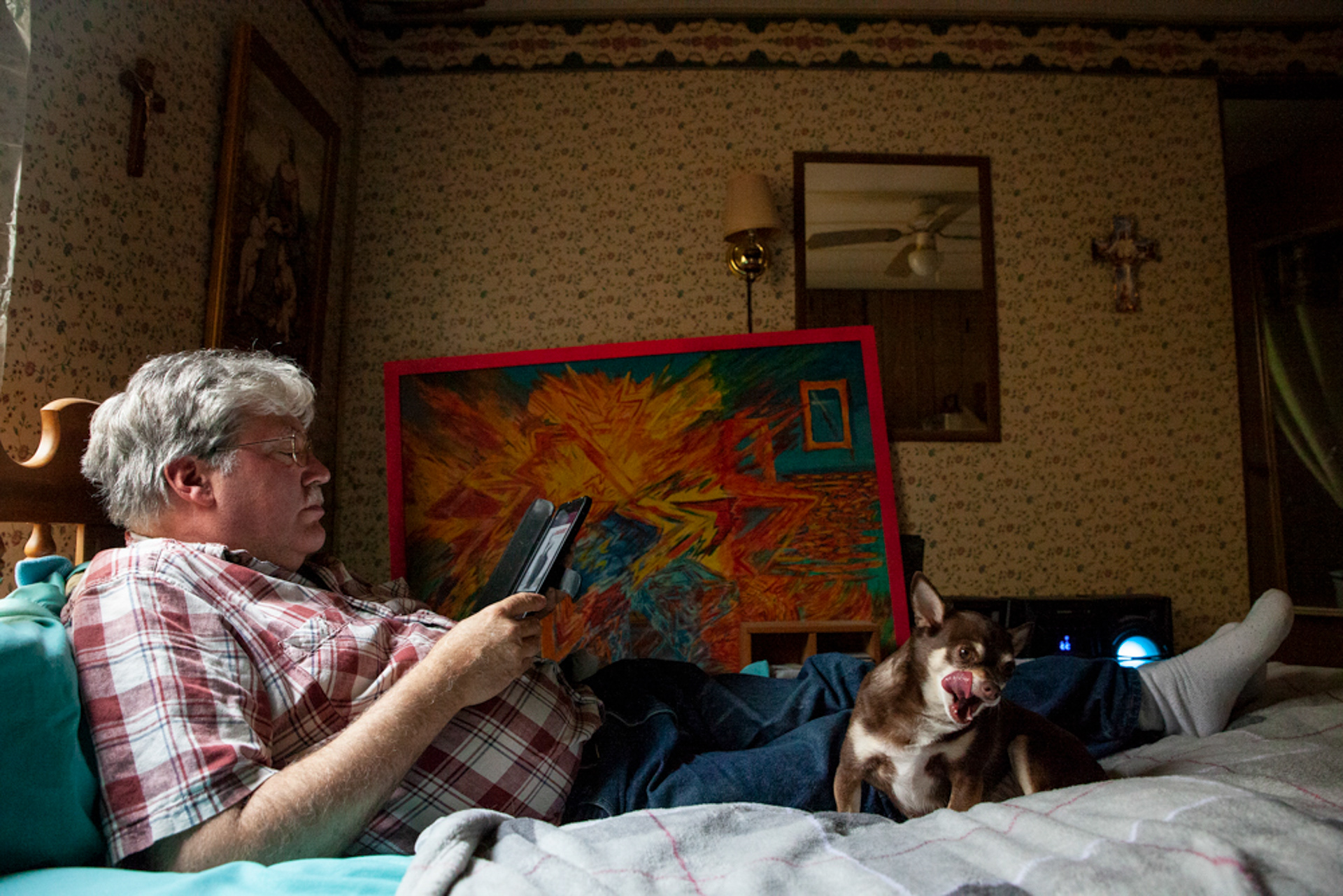 Christopher Ewing sits on his bed listening to German Gothic Metal with his seven year old chihuahua, Chipper, in his mobile home in Albany, Ohio. Behind Ewing, laid up against the wall, is a painting, named Prozac, he completed while in school, and also in solitary confinement at a mental hospital. During his confinement he pleaded with the doctors to take him off prozac, because it was, "making him violent."