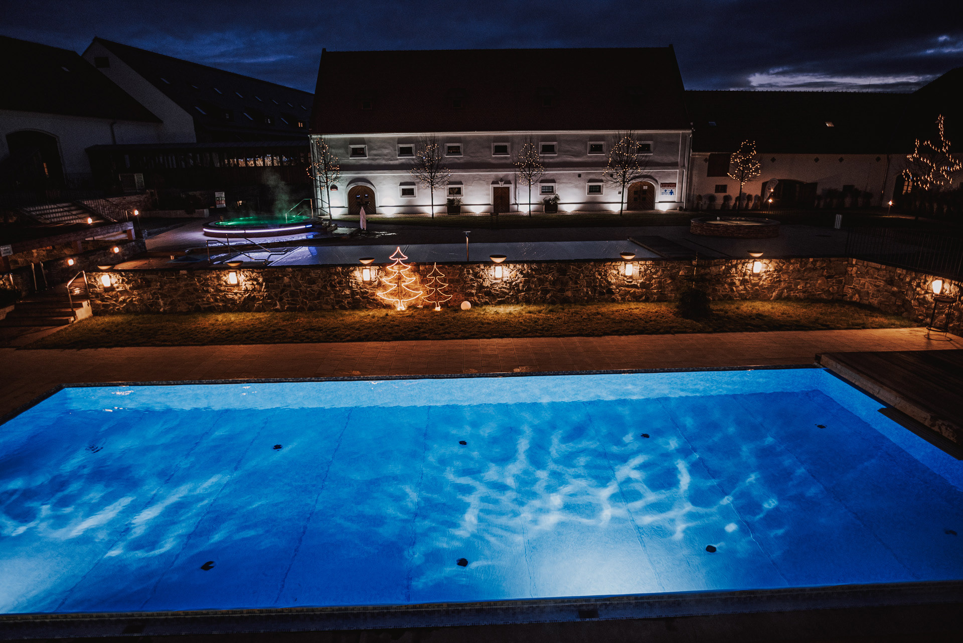 nasvícený bazén a budovy hotelu Zámek Valeč