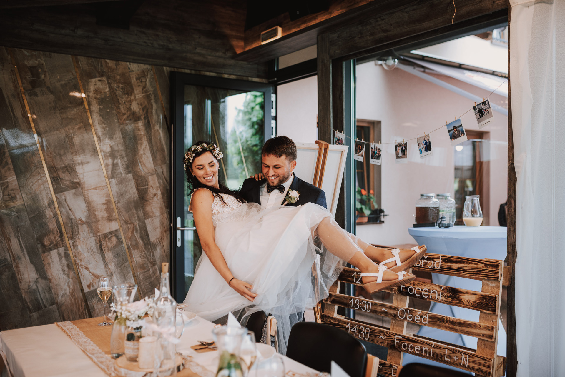 ženich přenáší nevěstu přes práh restaurace