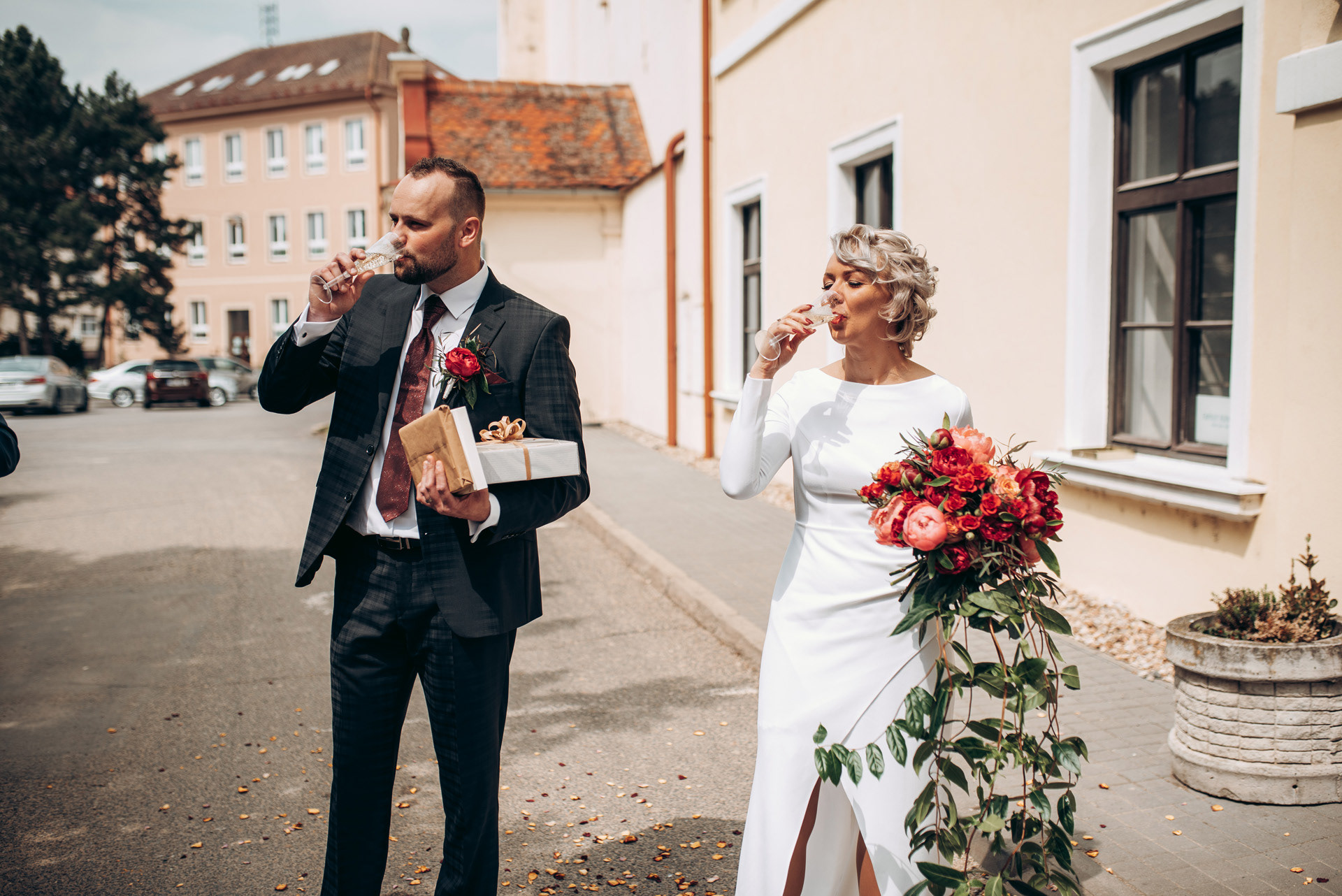 ženich s nevěstou si připíjejí před radnicí